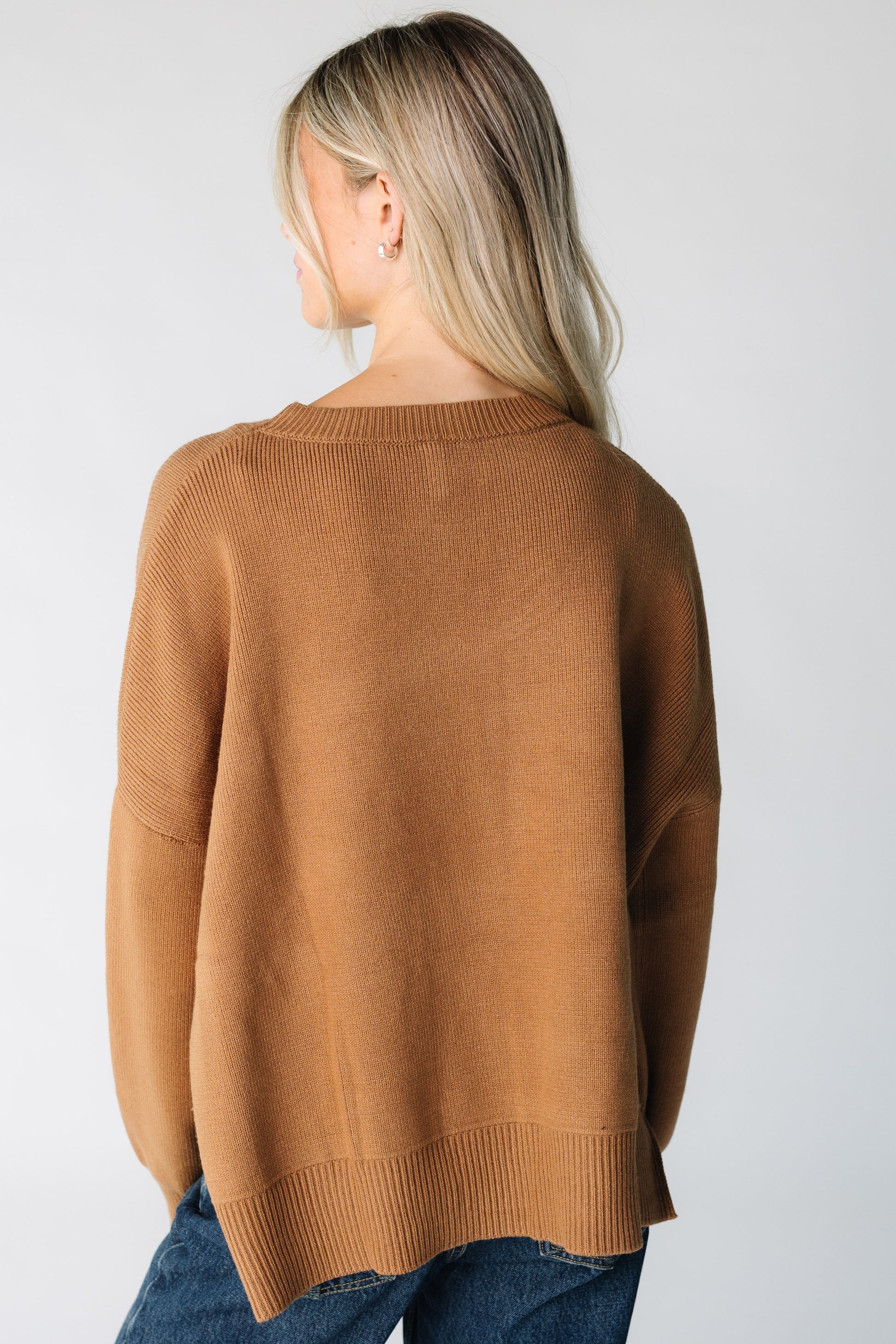 Back view of a woman wearing a brown loose fitting sweater with long sleeves