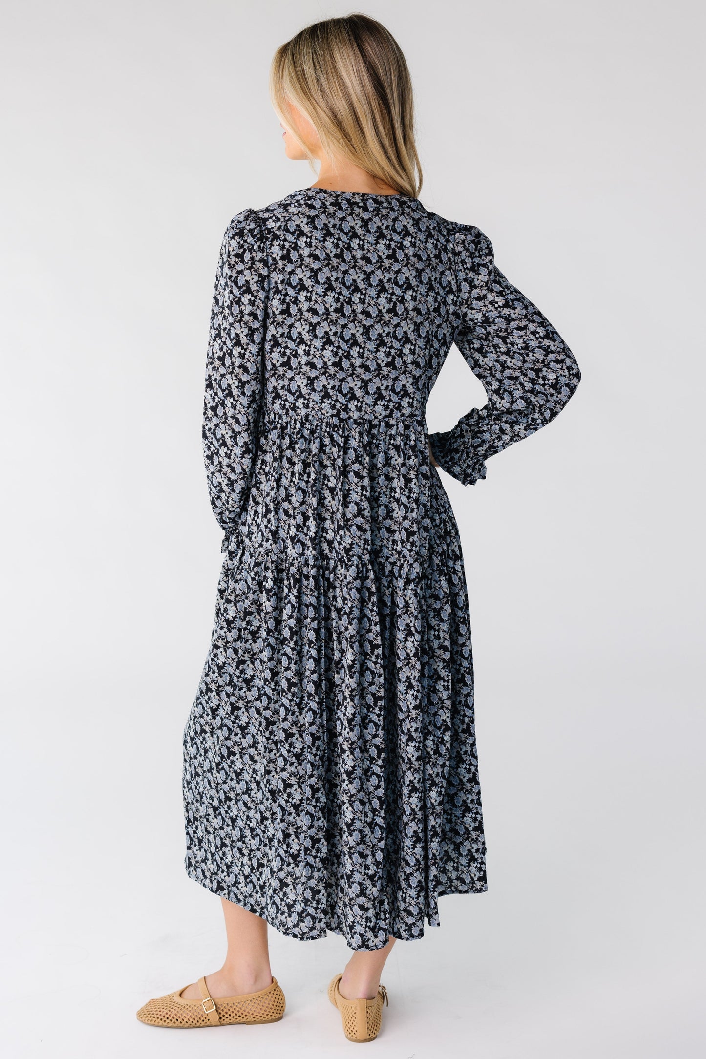 Back view of a woman wearing a blue floral dress with long sleeves