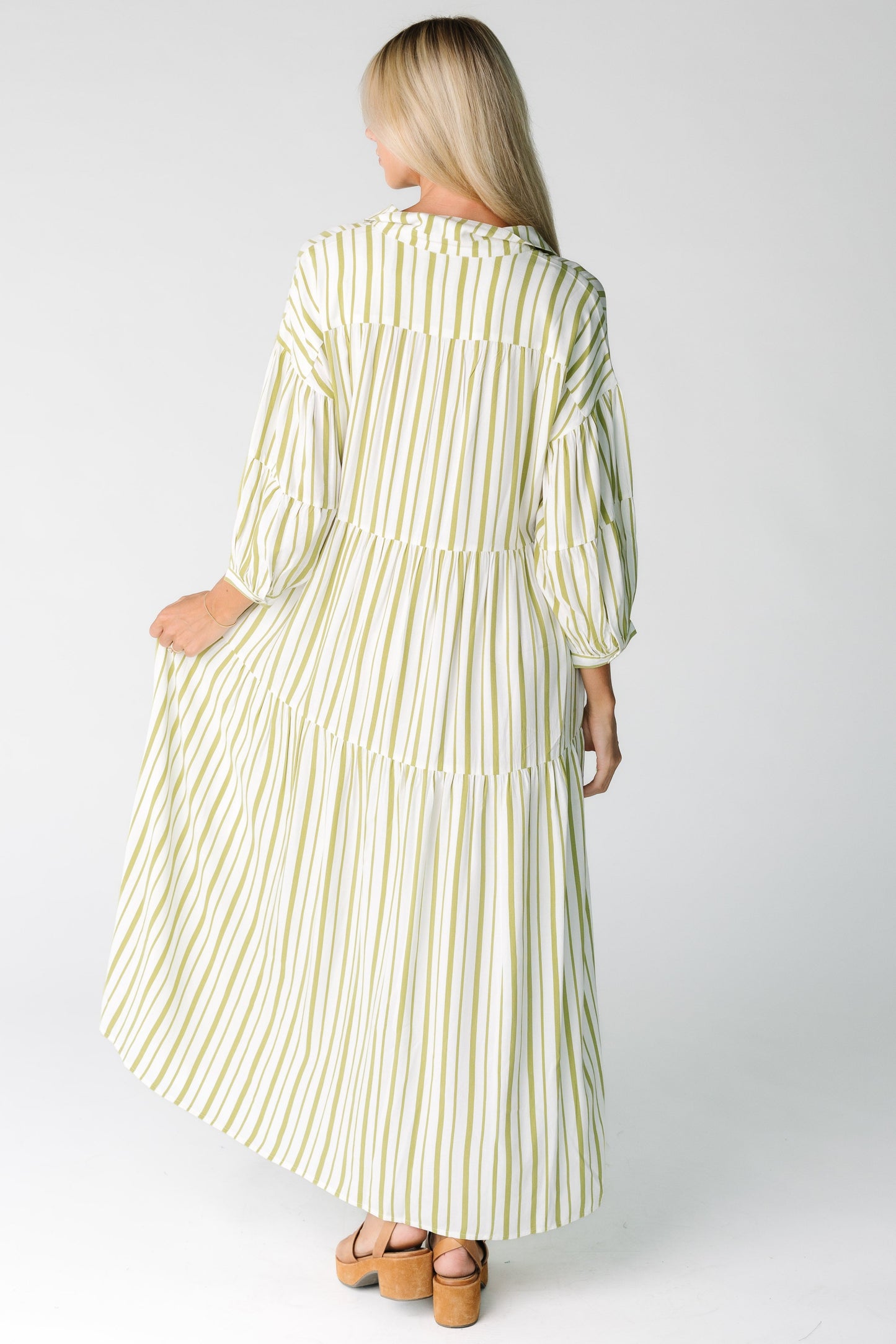 Back view of a woman in an ivory and green stripe midi dress