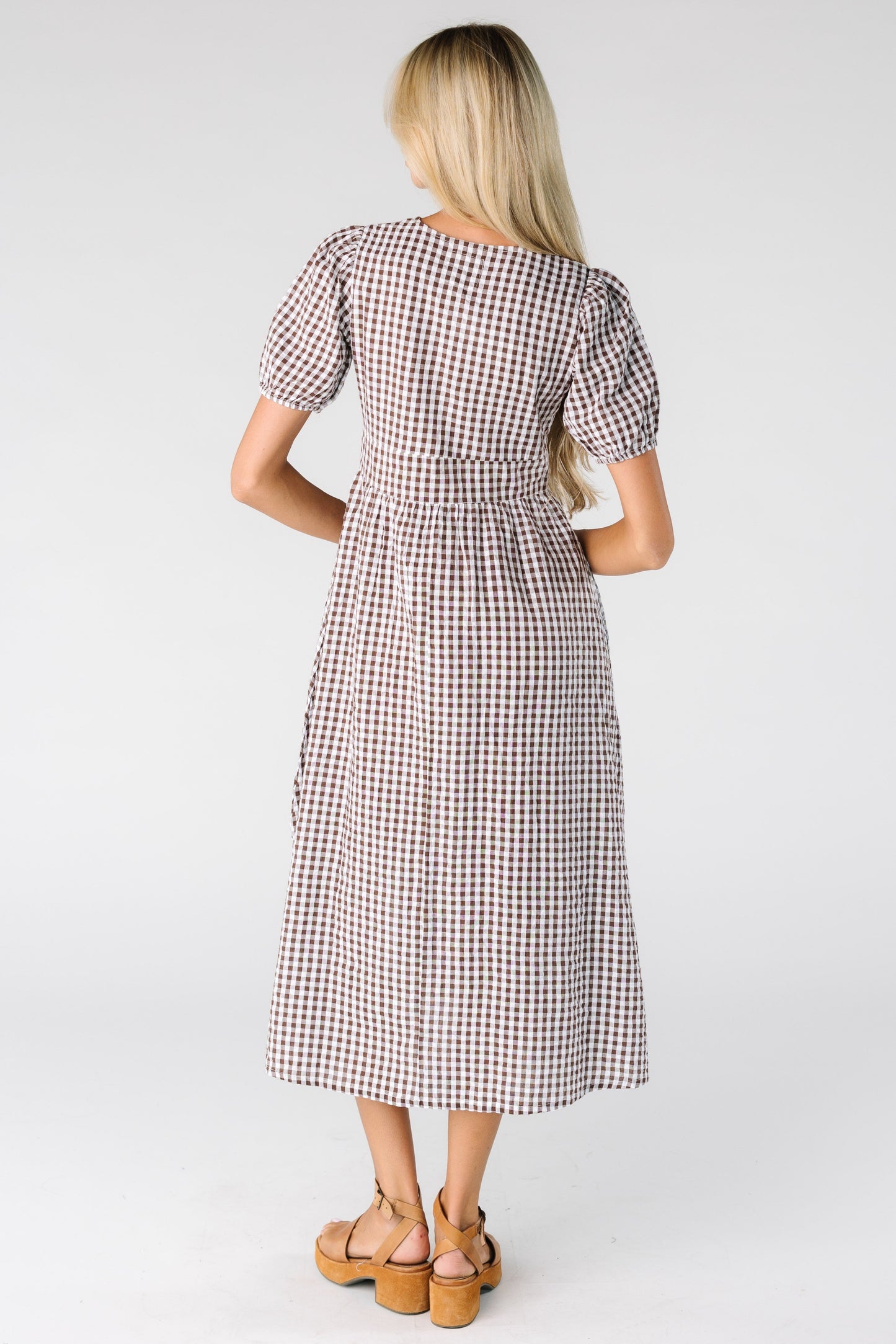 Back view of a woman wearing a brown and white gingham midi dress