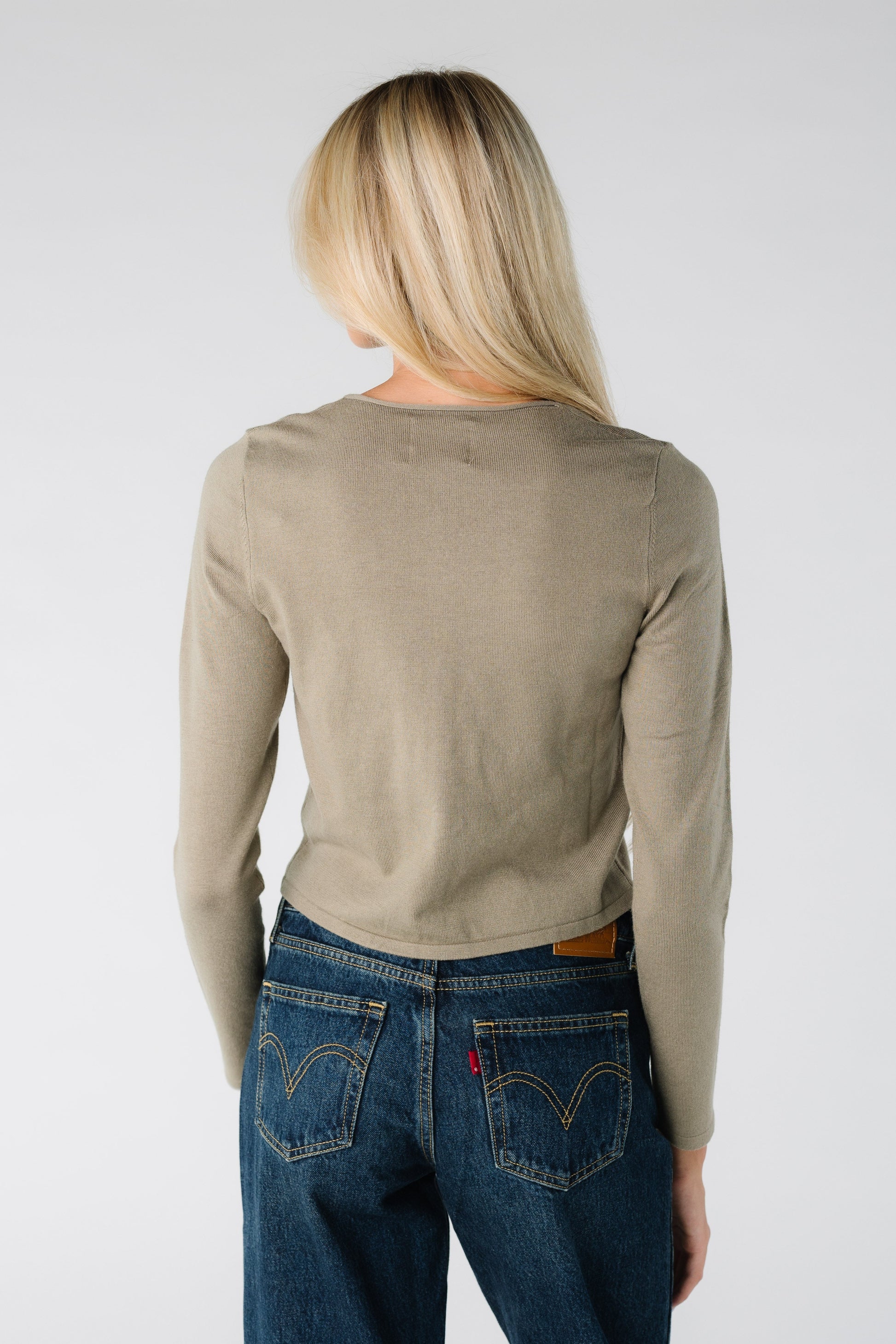 Back view of a woman wearing a long sleeve cardigan in olive