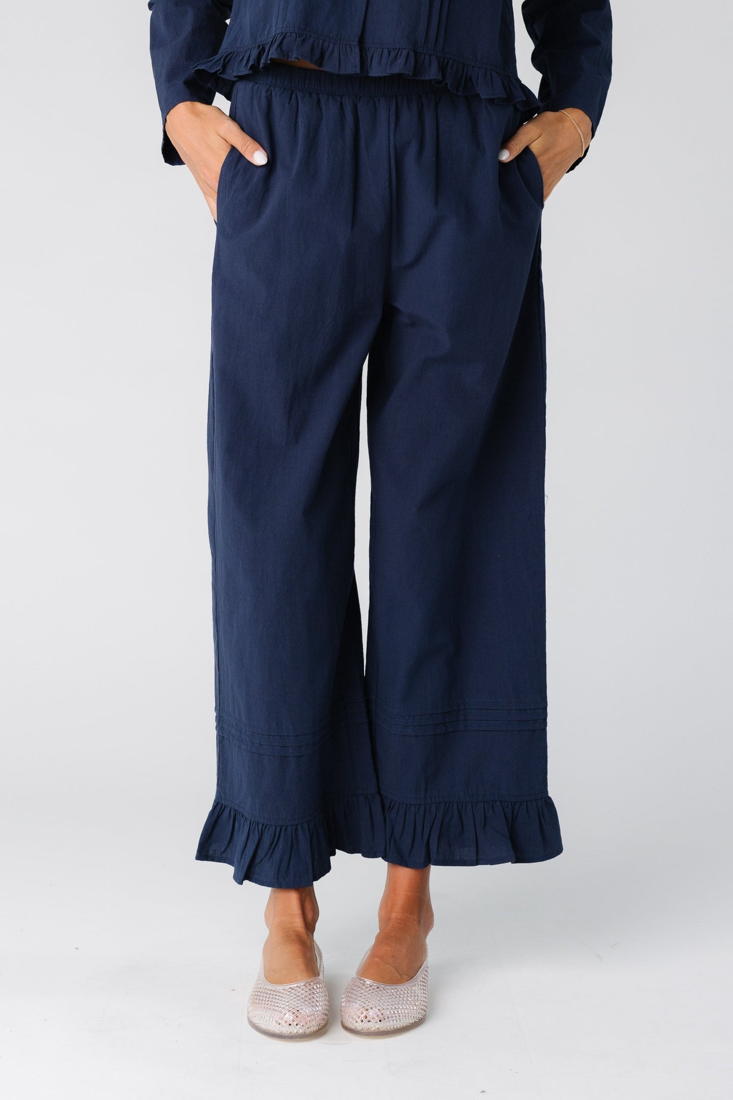 Woman wearing a navy wide leg pant with ruffle hem