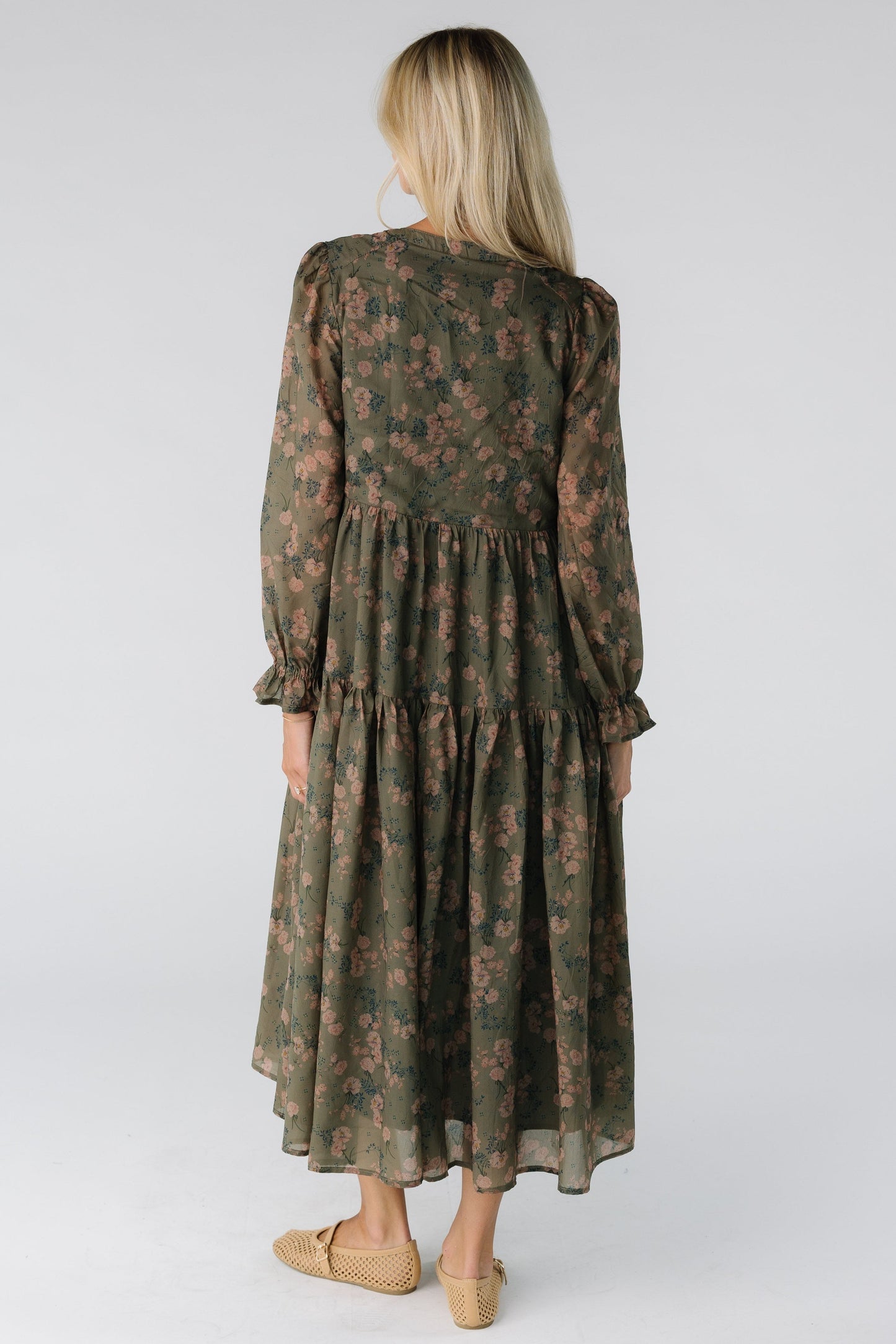 Back view of a woman wearing an olive floral dress with long sleeves