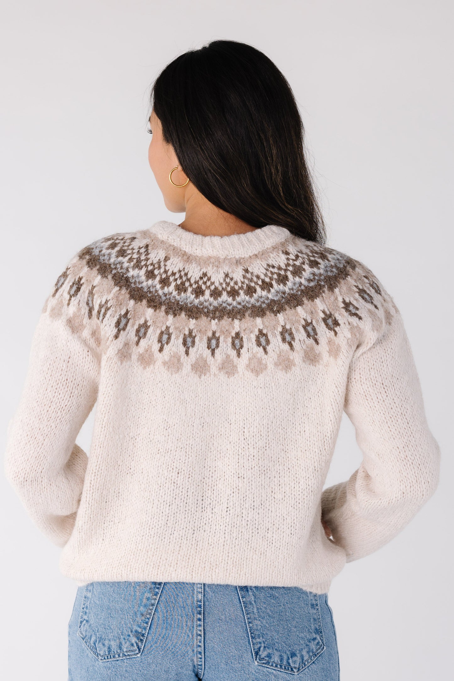 Back view of a woman wearing an ivory sweater with long sleeves