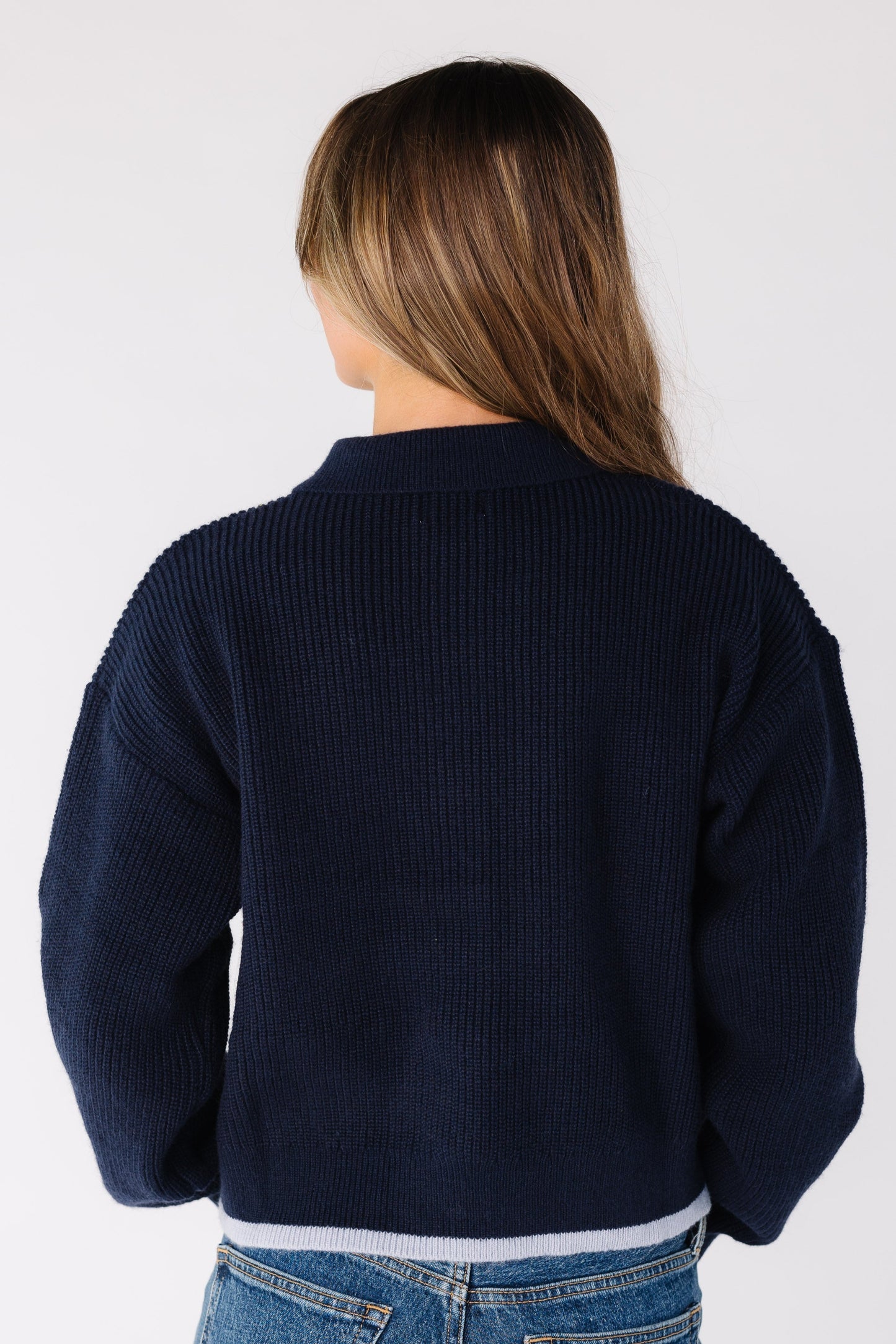 Back view of a woman wearing a navy ribbed cardigan