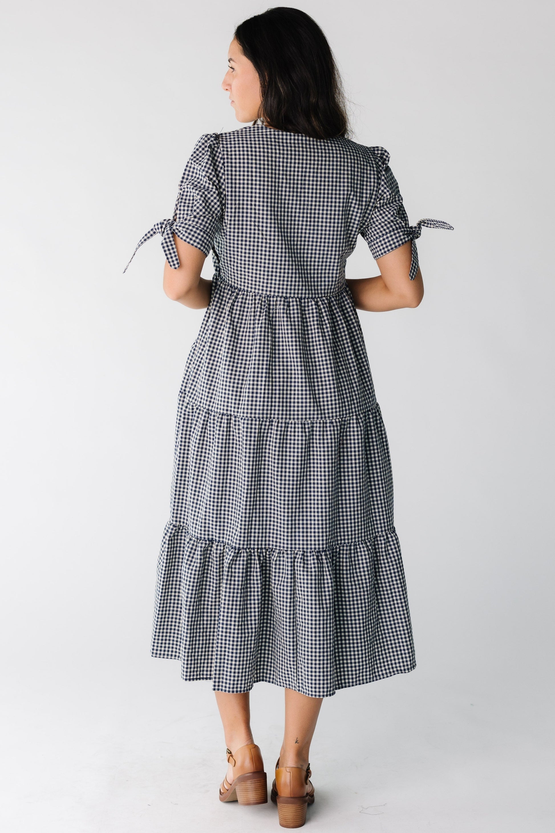 Back view of a woman wearing a navy gingham tiered midi dress