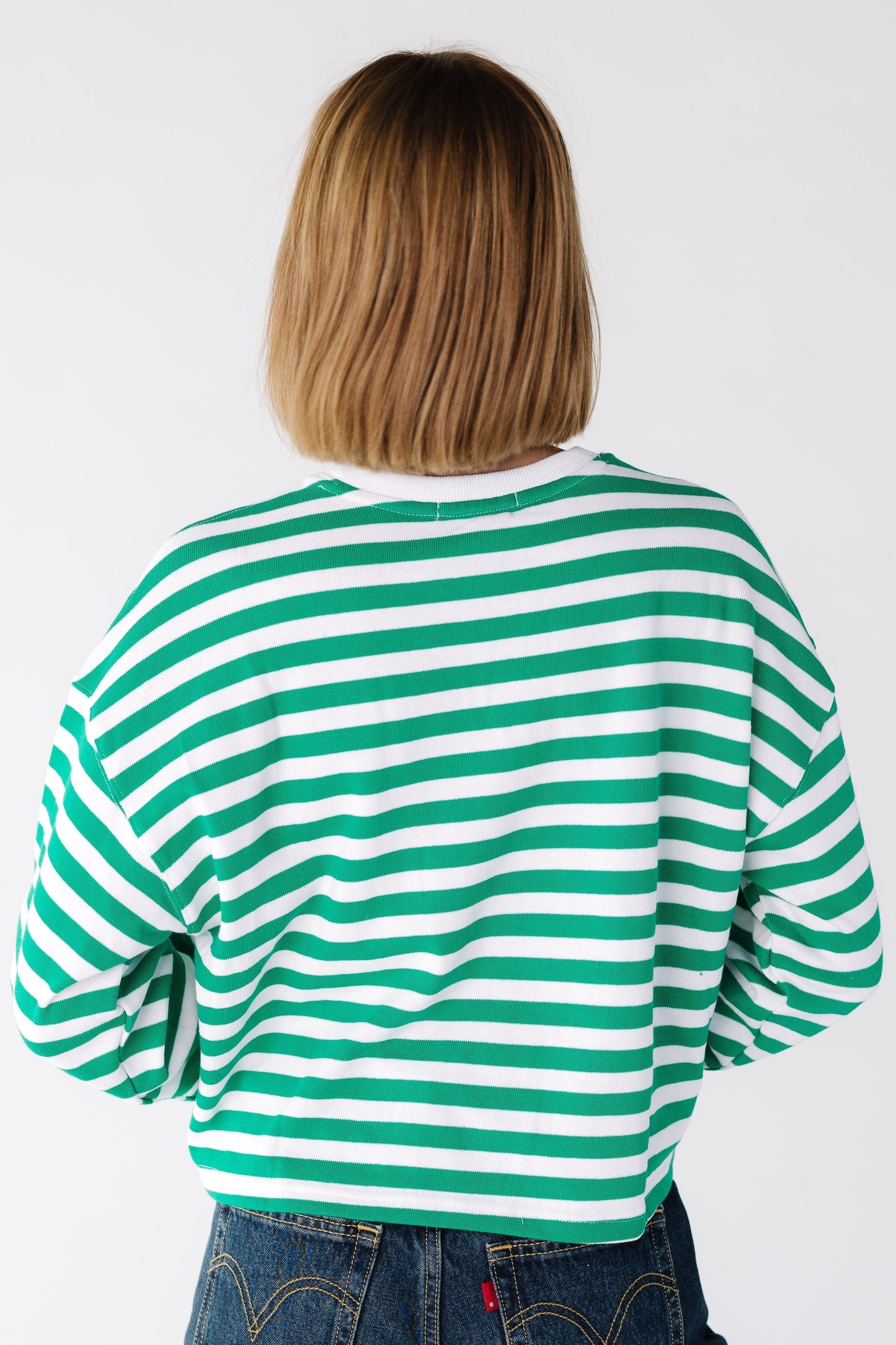 Back view of a woman wearing a green and white stripe top with long sleeves
