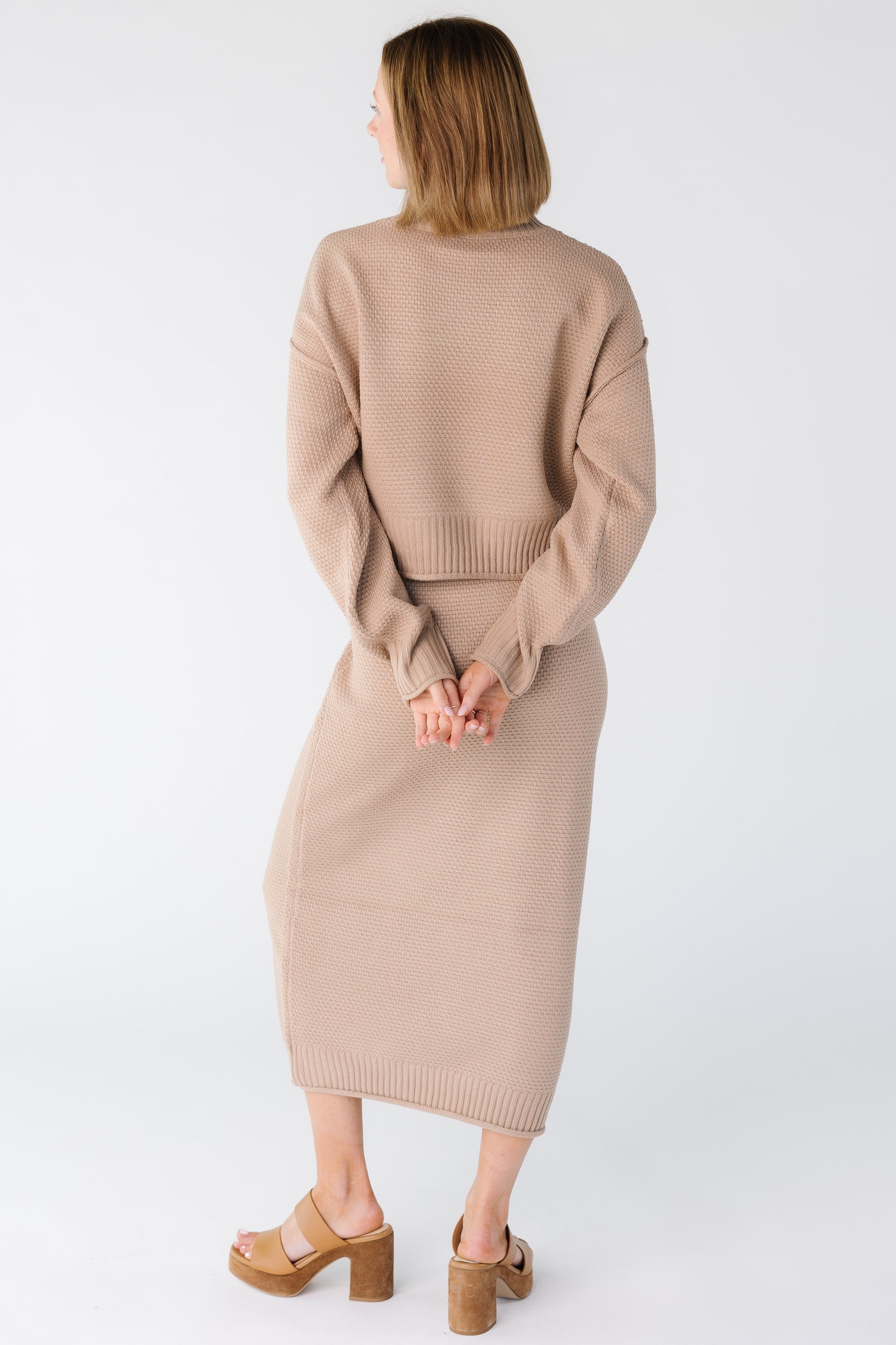 Back view of a woman wearing a taupe sweater and skirt set