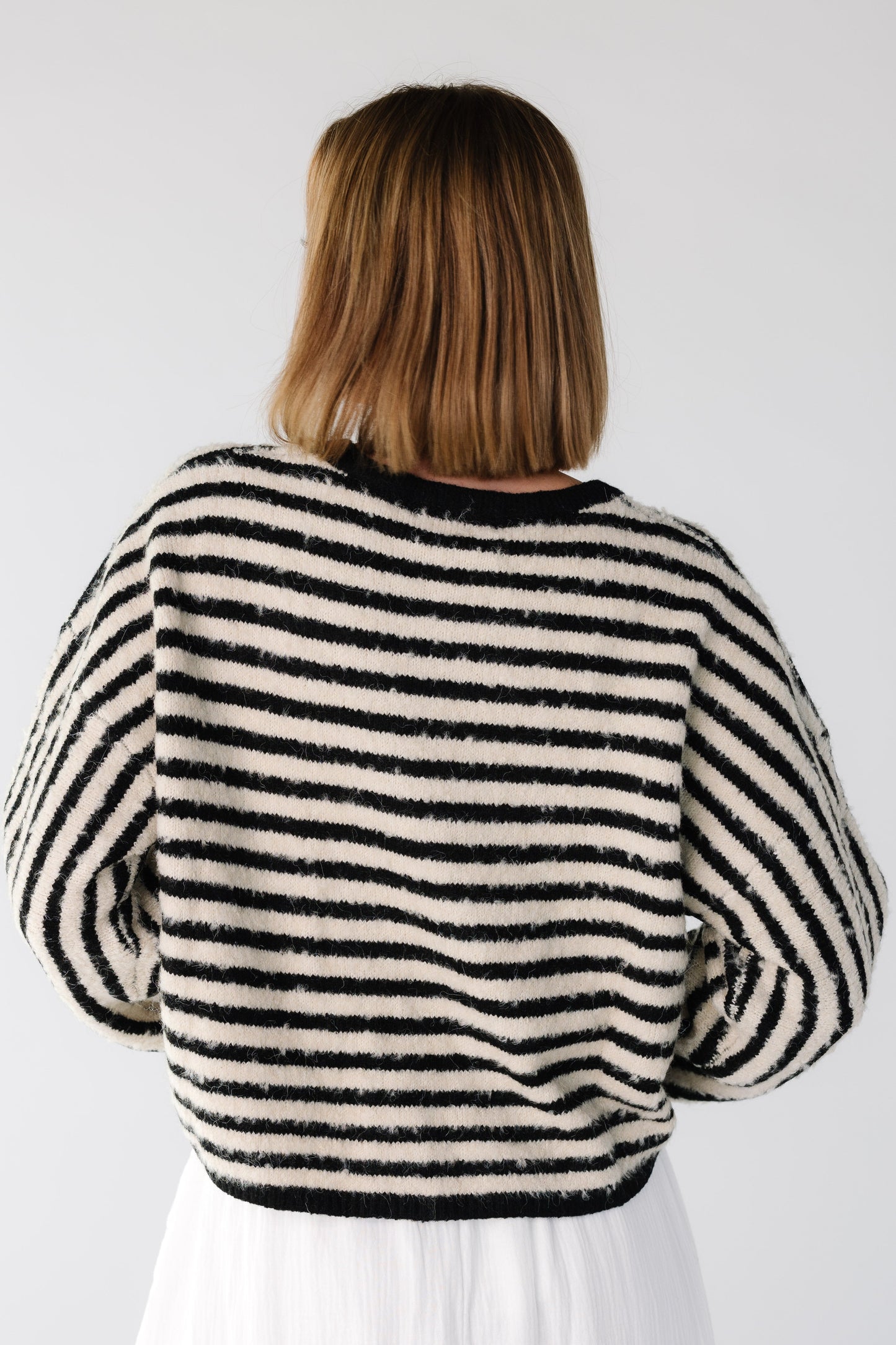 Back view of a woman wearing a long sleeve black and white stripe sweater