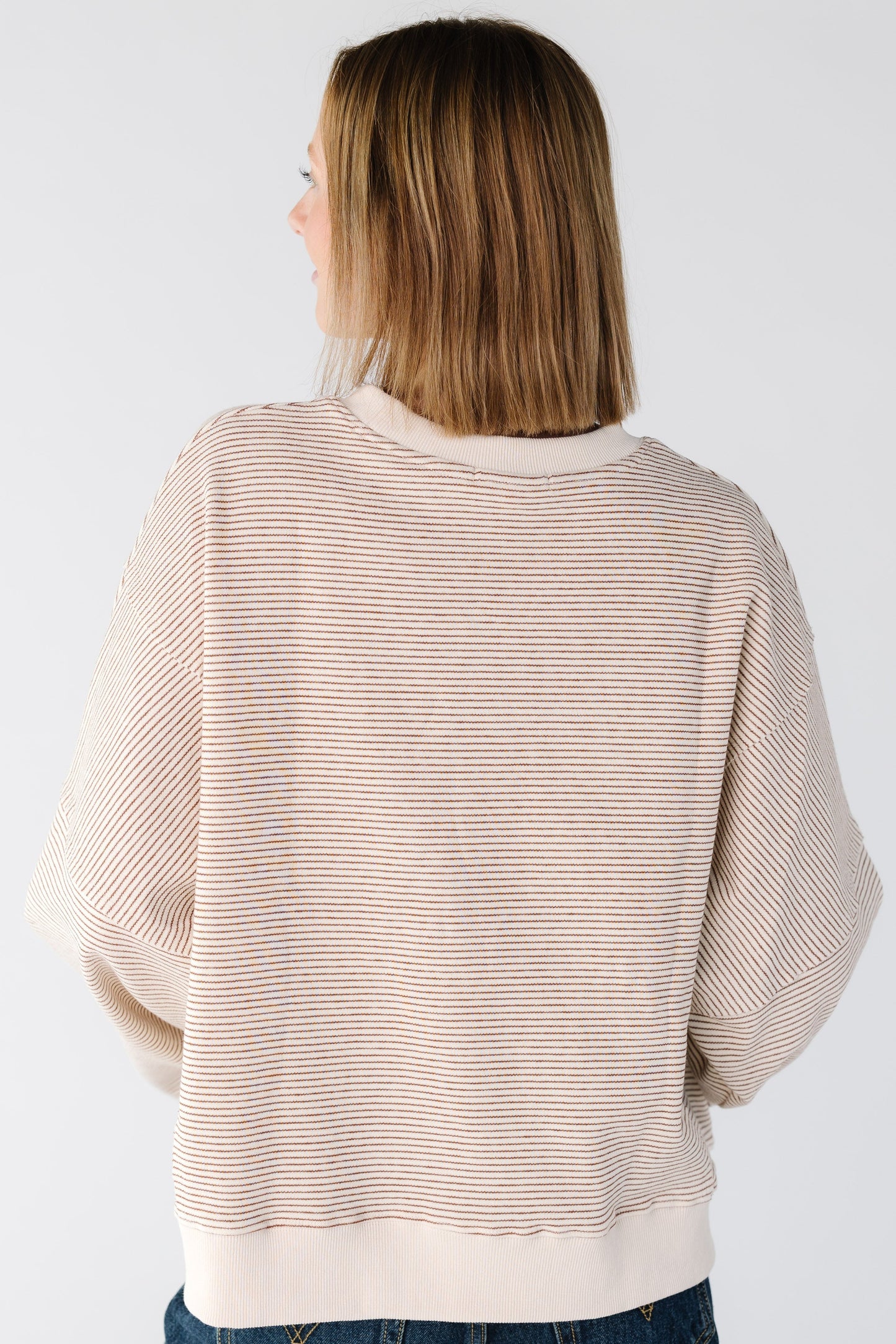 Back view of a woman wearing a camel stripe sweatshirt