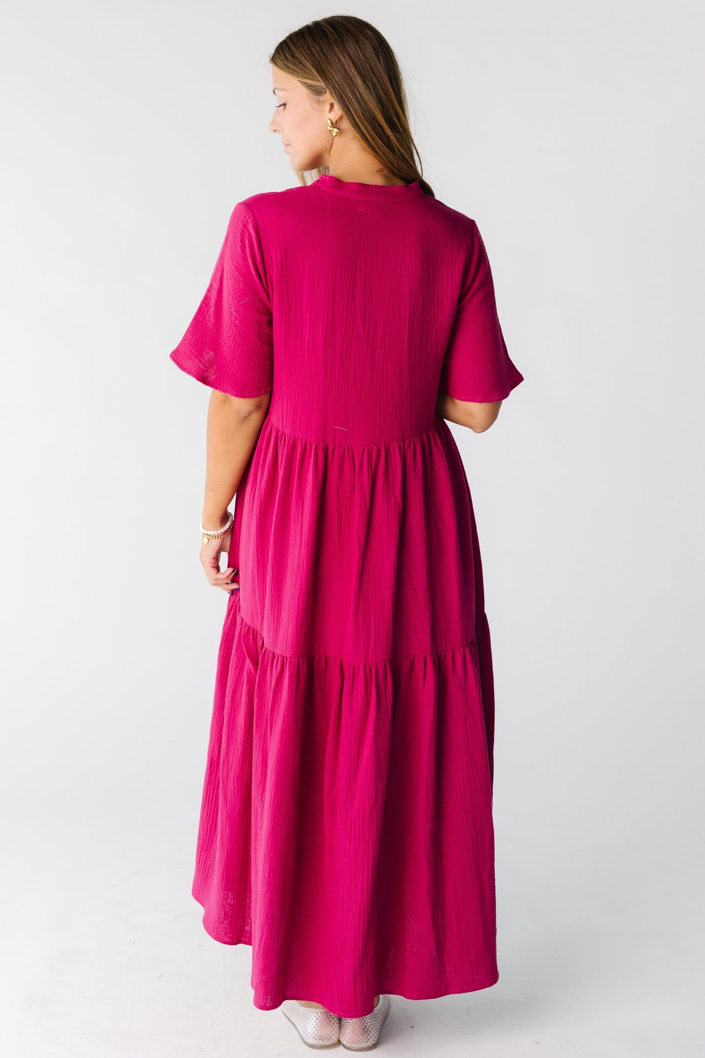 Back view of a woman wearing a  fuchsia midi maxi dress with short sleeves