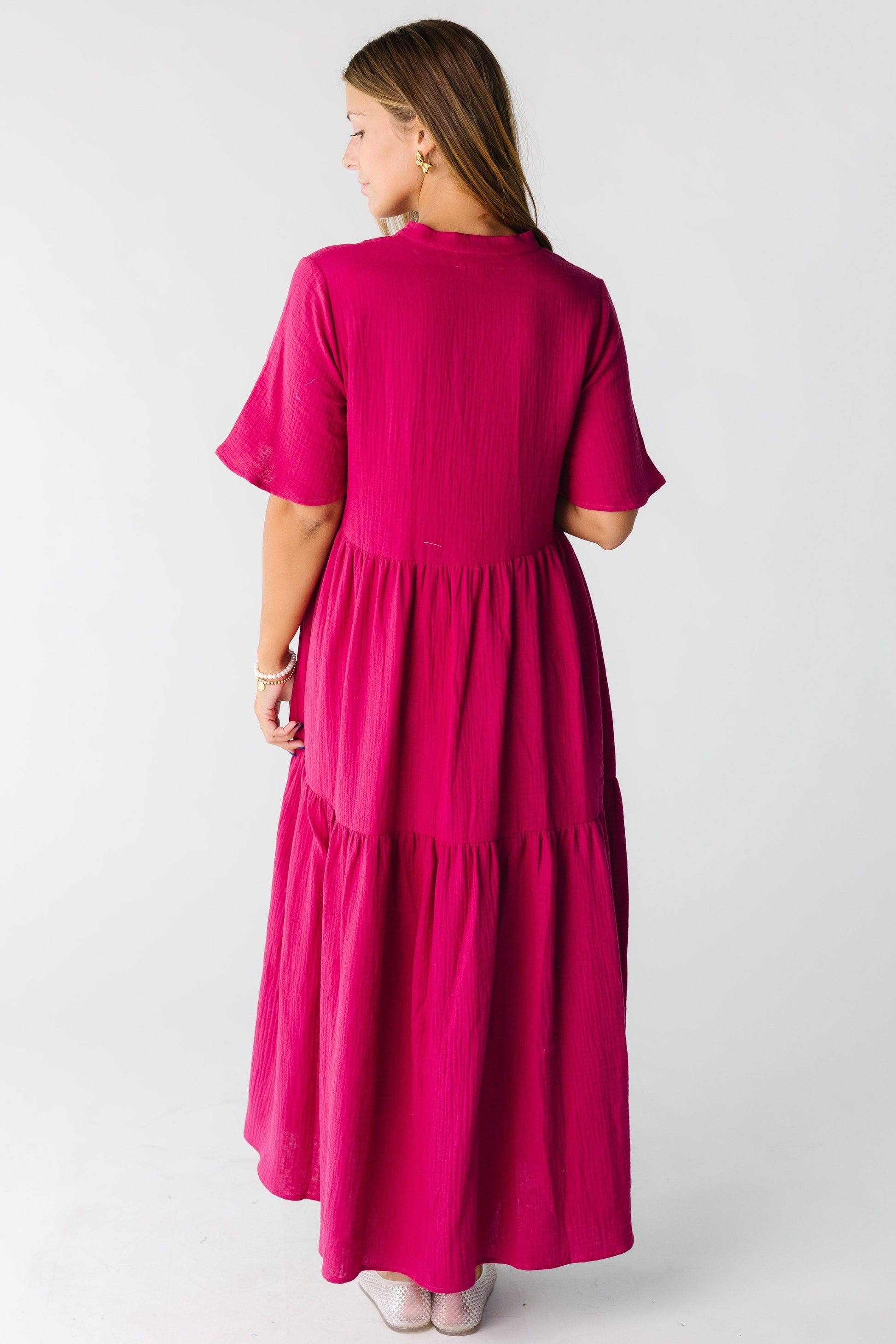 Back view of a woman wearing a  fuchsia midi maxi dress with short sleeves