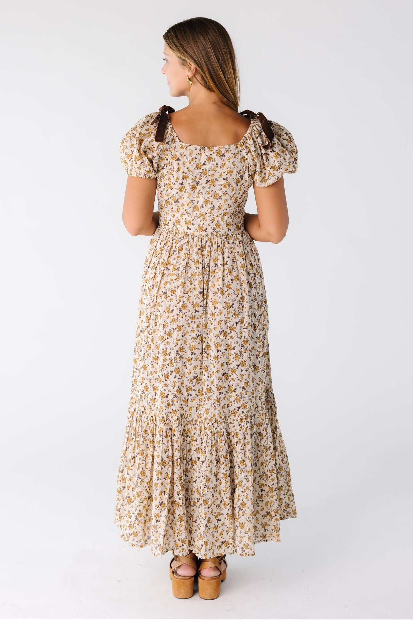 Back view of a woman wearing a gold floral midi maxi dress with short sleeves