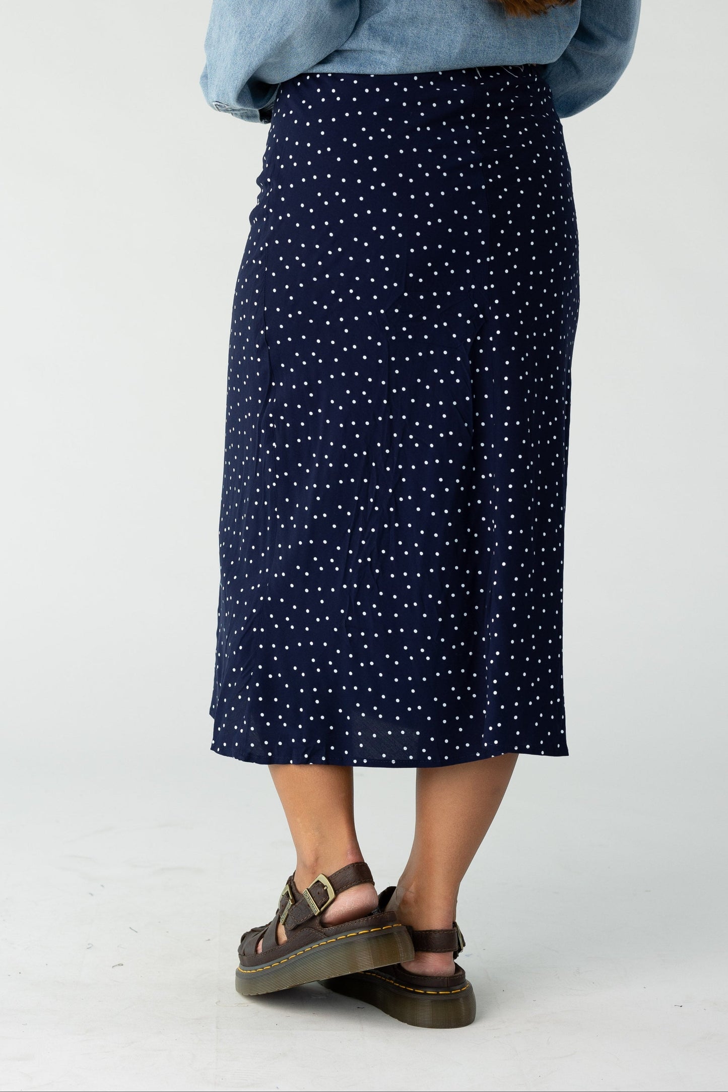 Back view of a woman wearing a navy polka dot midi skirt