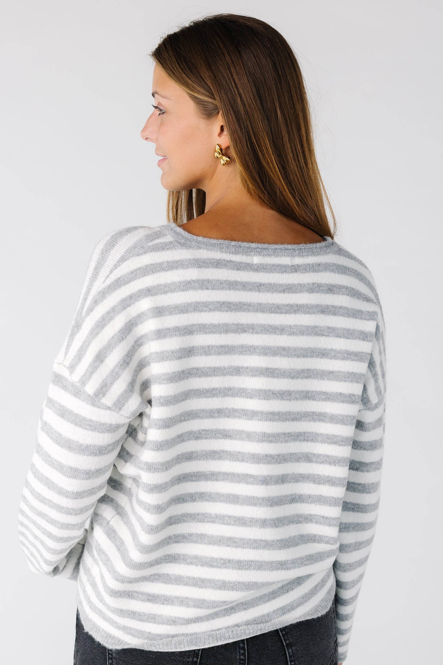 Back view of a woman wearing a grey and white stripe cardigan with long sleeves