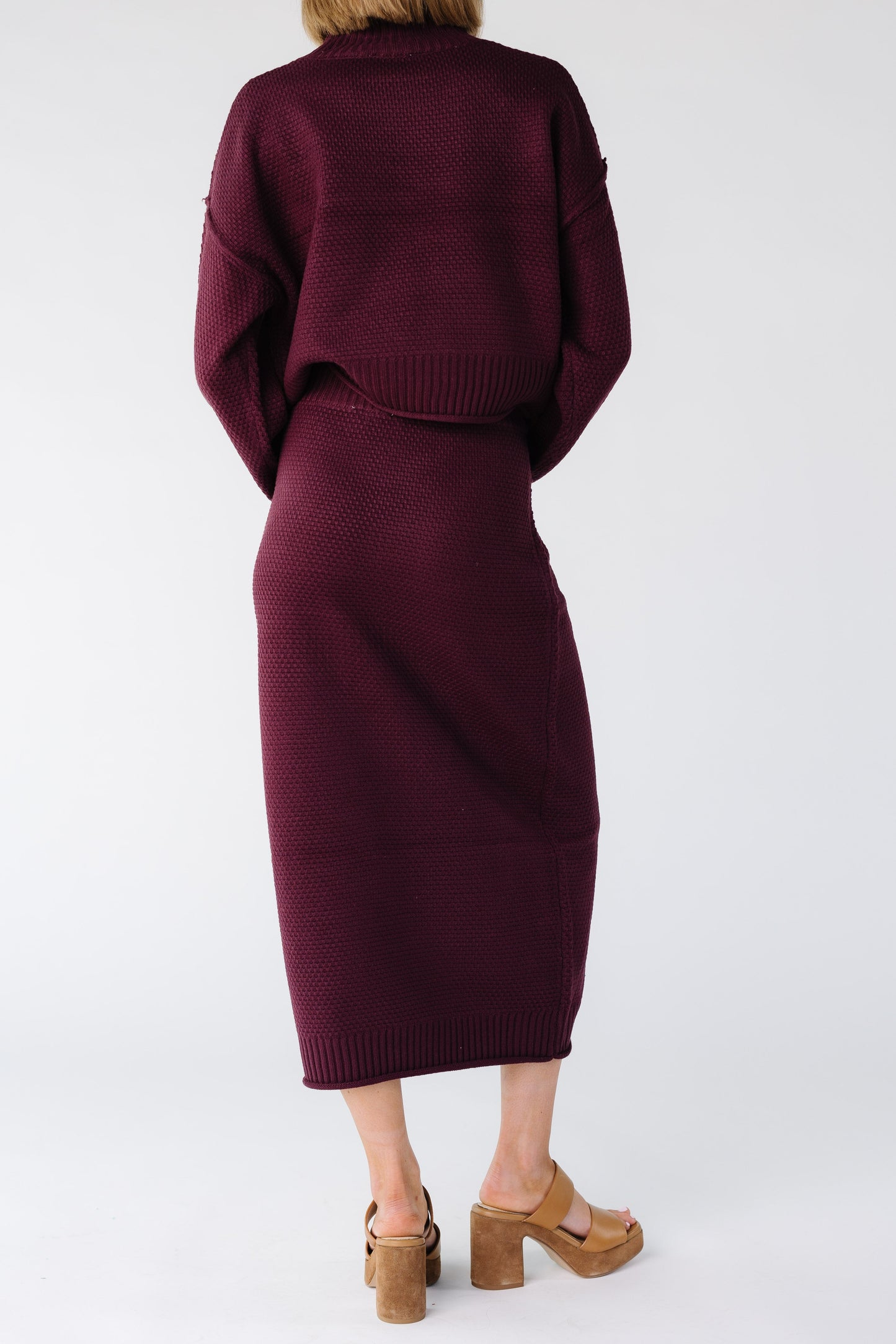 Close view of a woman wearing a burgundy closer fitting a midi length pencil skirt