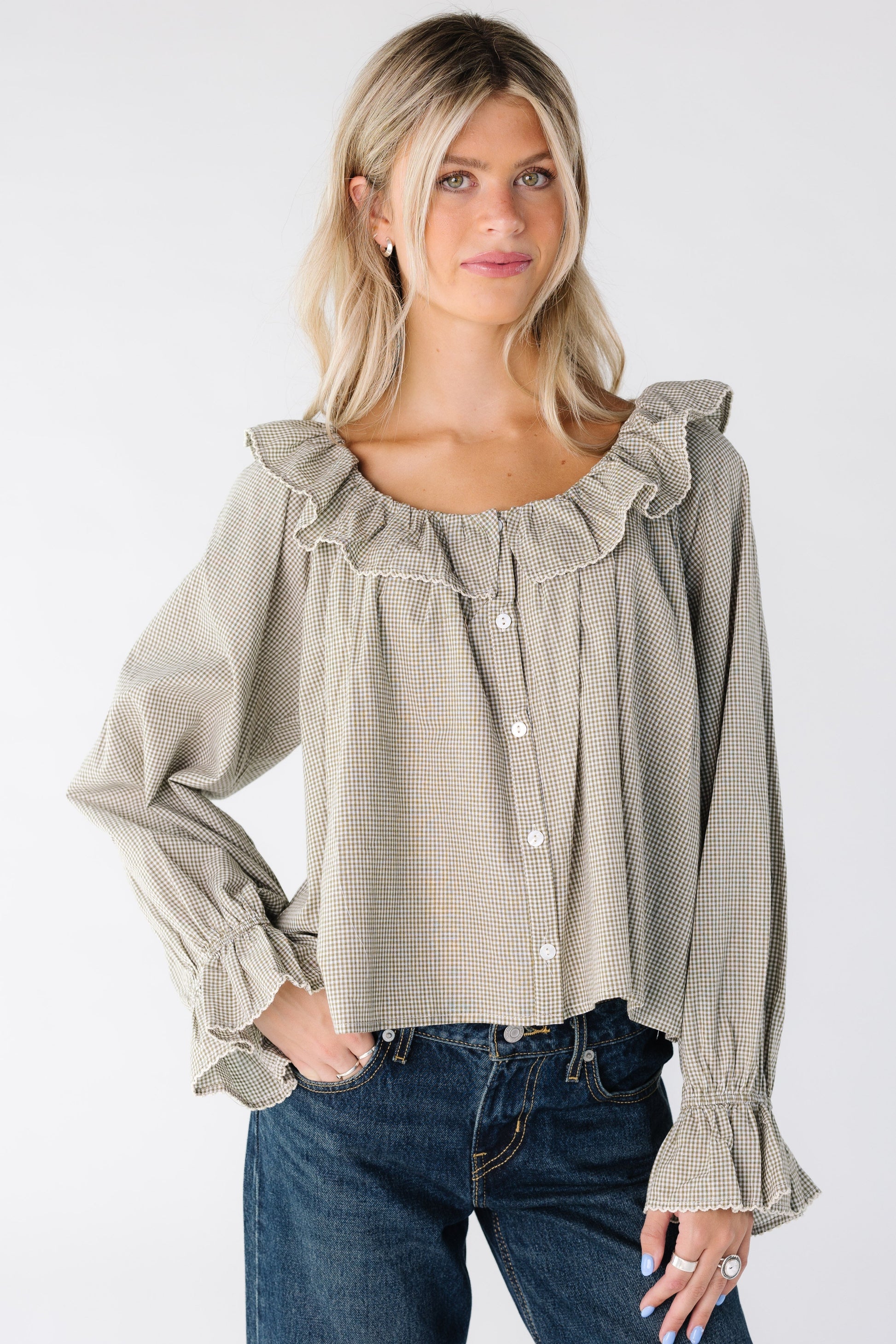 Woman wearing a sage and white gingham button down top with ruffle collar