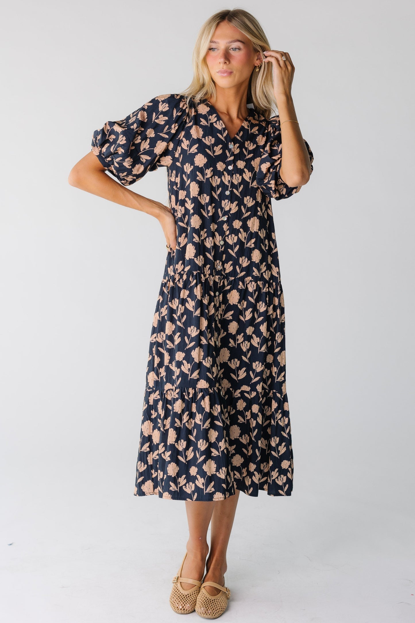 A woman wearing a navy floral dress with short sleeves