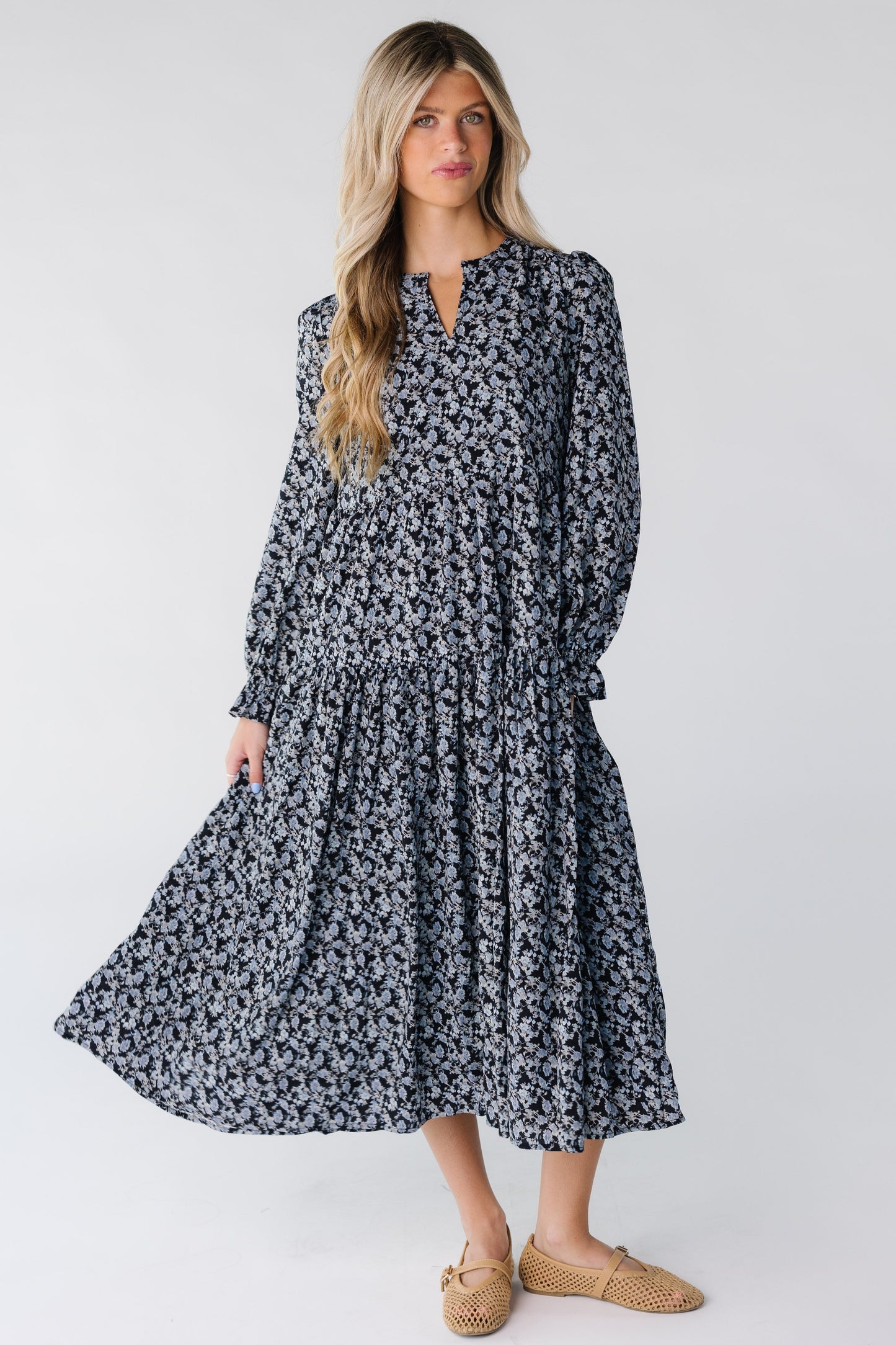 A woman wearing a midi dress with long sleeves and V-neckline