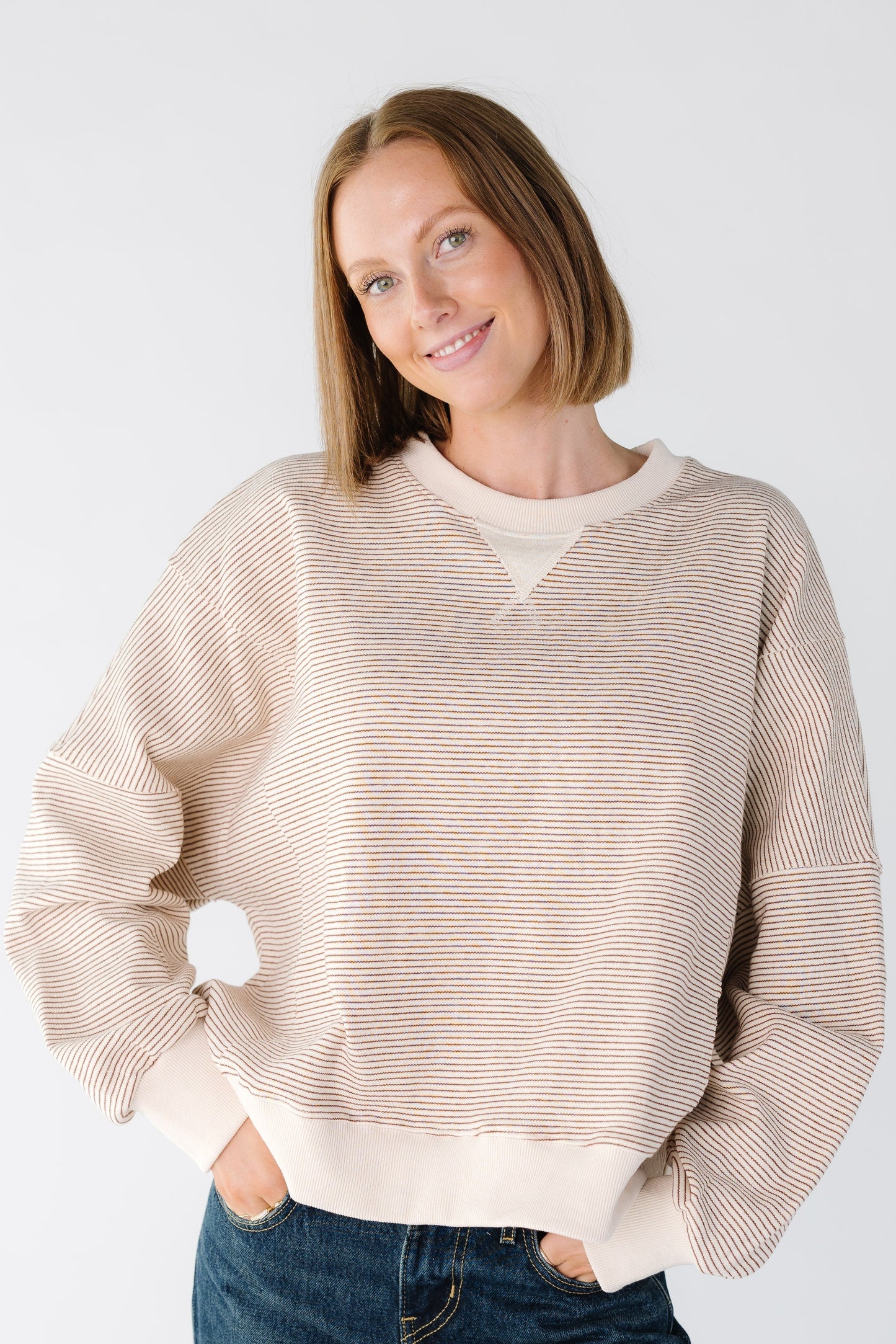 Women wearing a camel and ecru stripe sweatshirt with a solid ecru cuffs