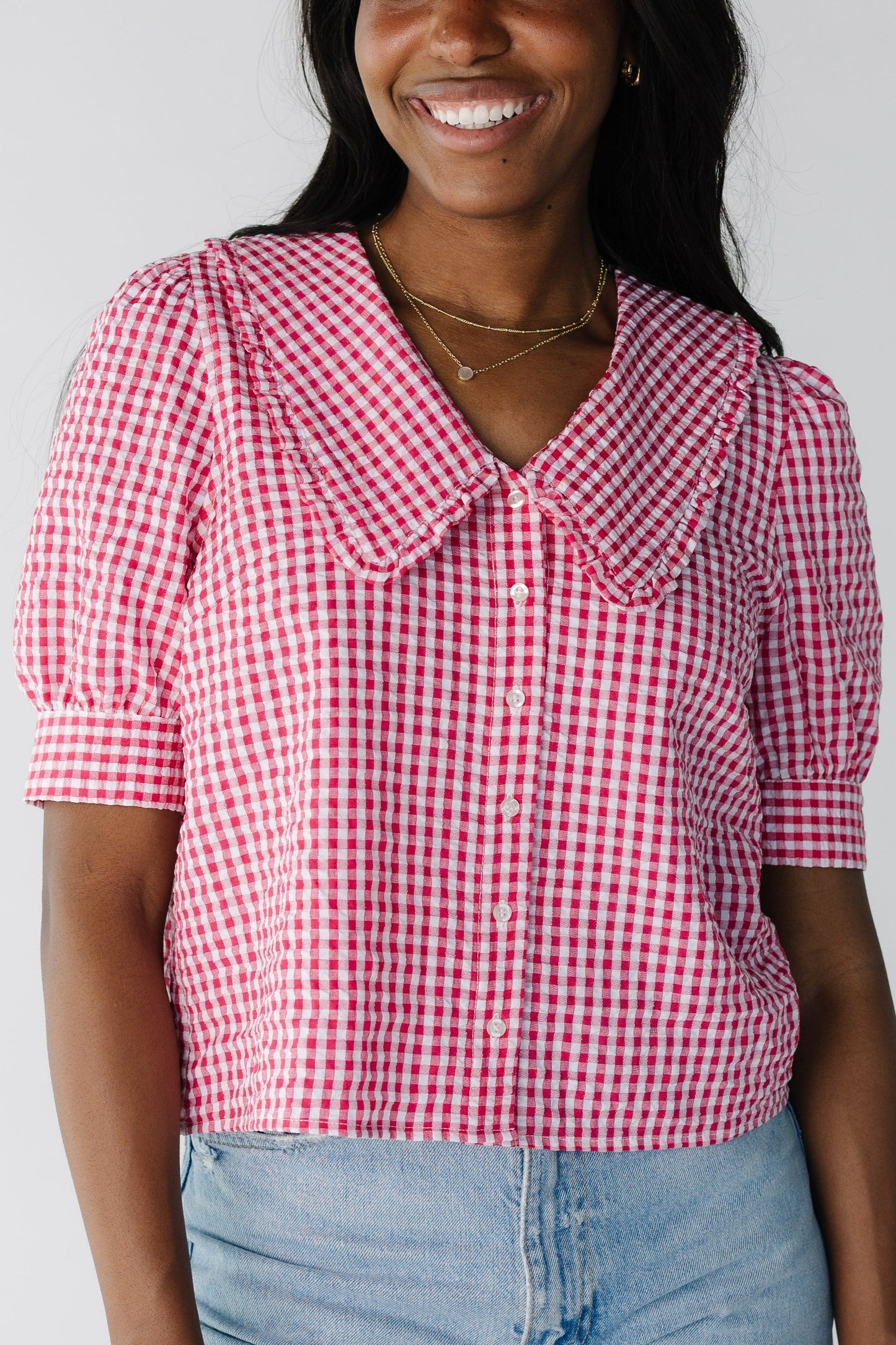 Close view of red gingham button down top with wide collar