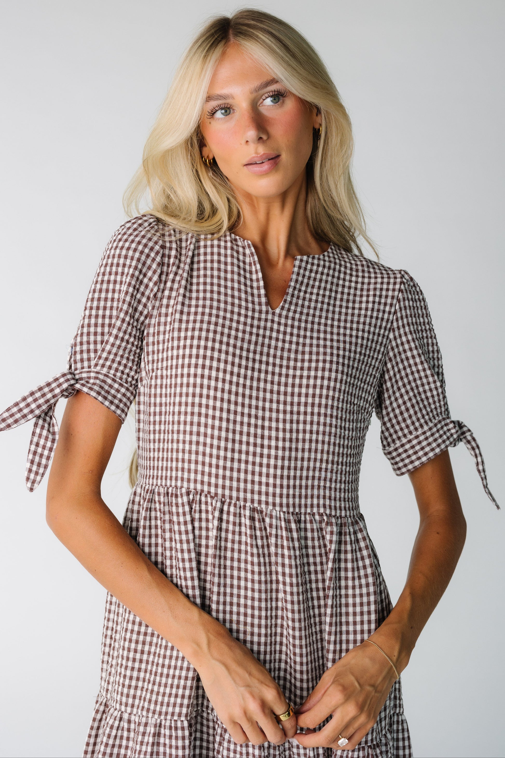 Close view of a woman wearing a brown gingham dress with short sleeves with ties