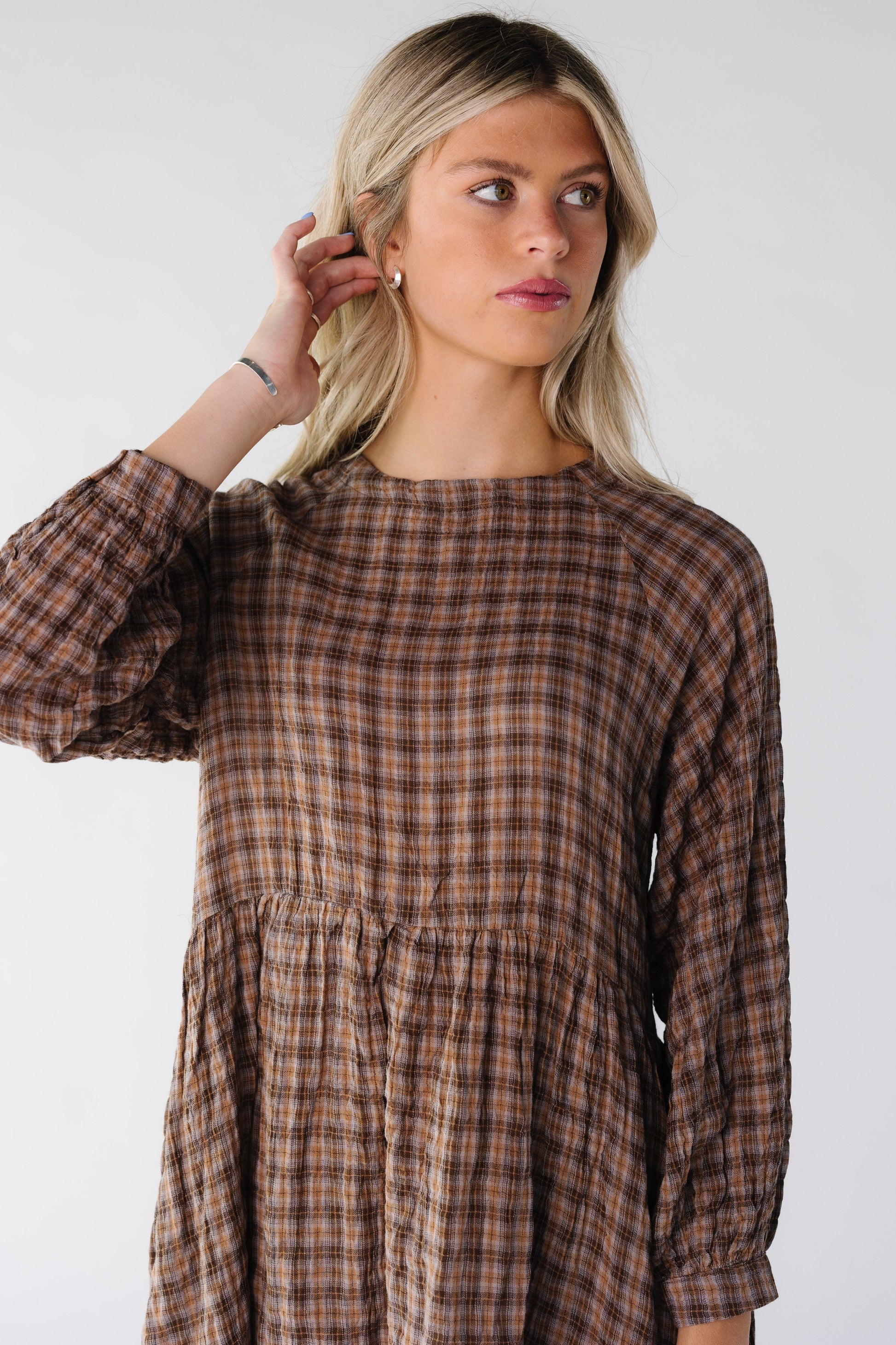 Woman wearing a light brown plaid dress with long sleeves
