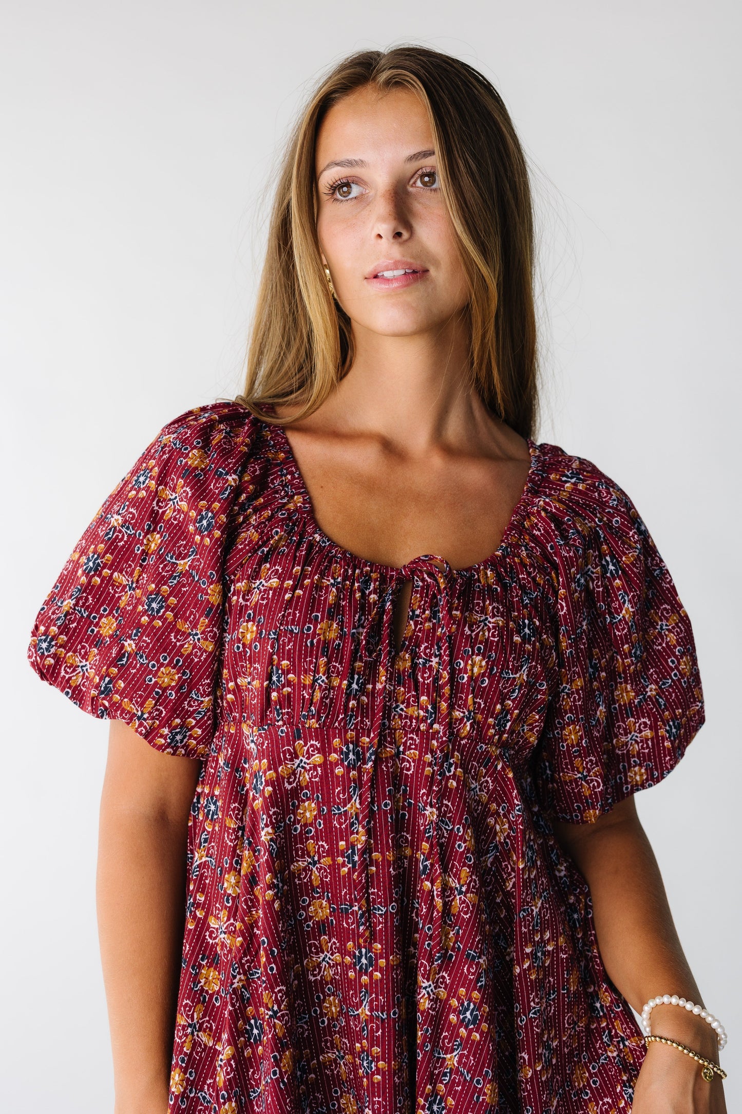Close view of a woman wearing a burgundy floral dress with scoop neckline