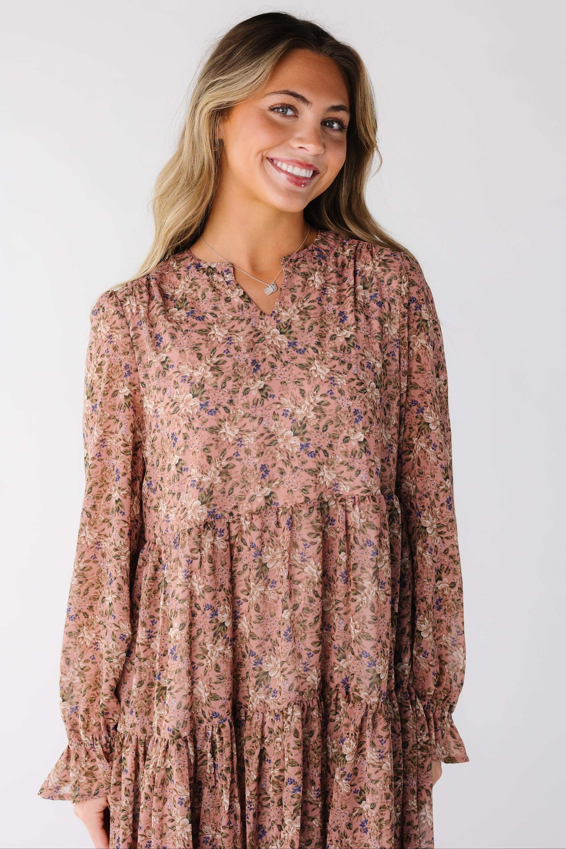 Close view of a woman wearing a mauve floral dress with long sleeves