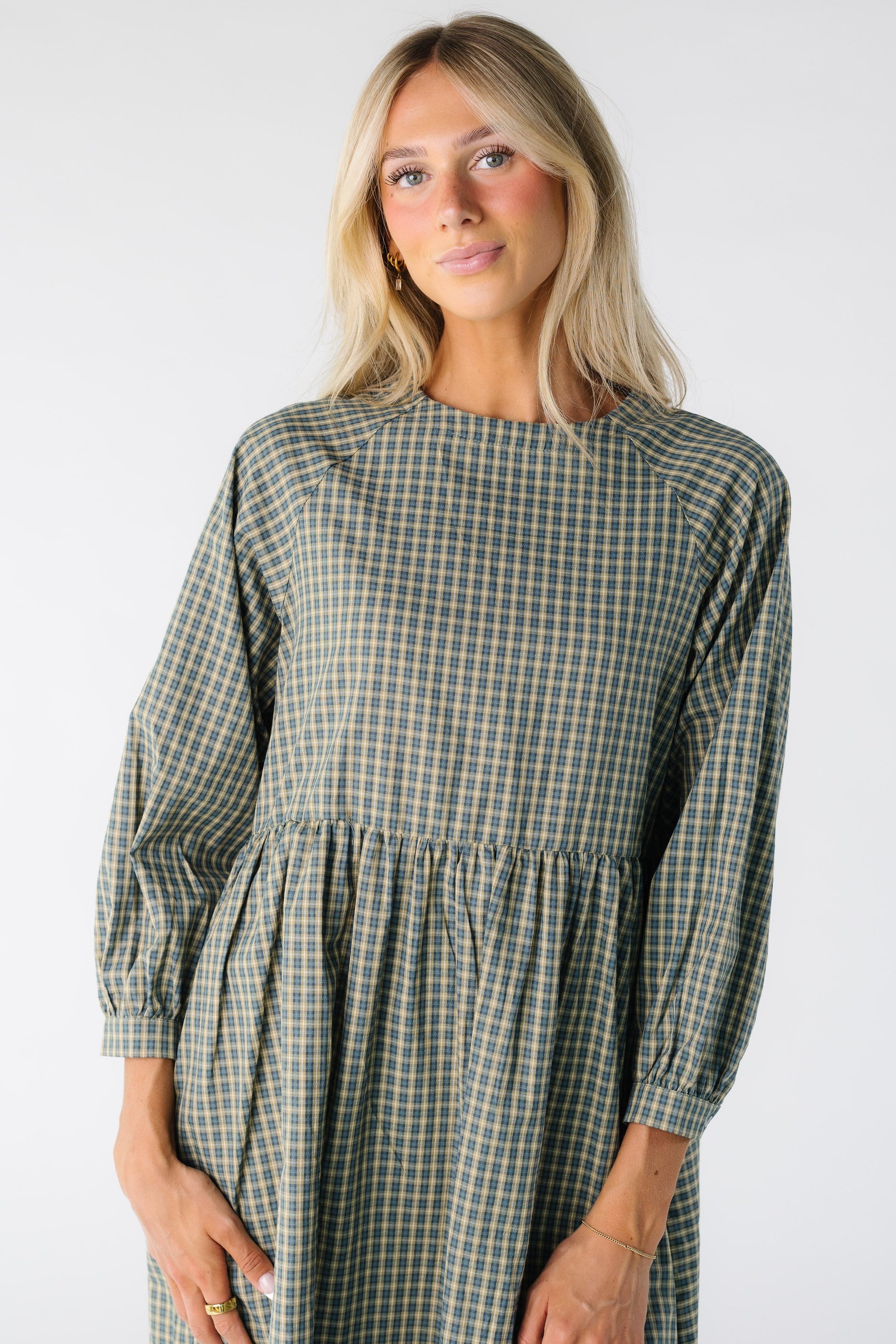 Close view of a woman wearing a green plaid dress with long sleeves