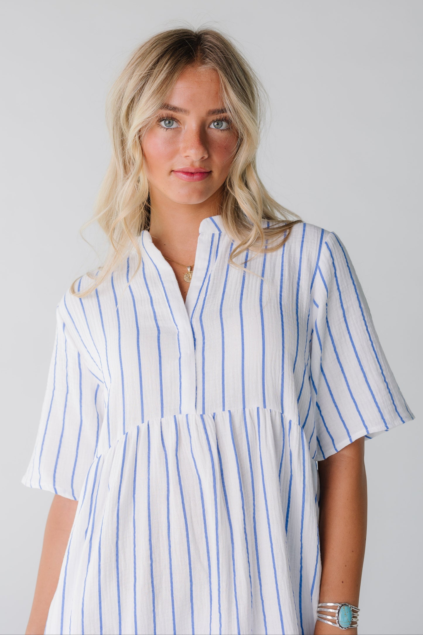 Close view of woman wearing white and blue stripe dress with short sleeves