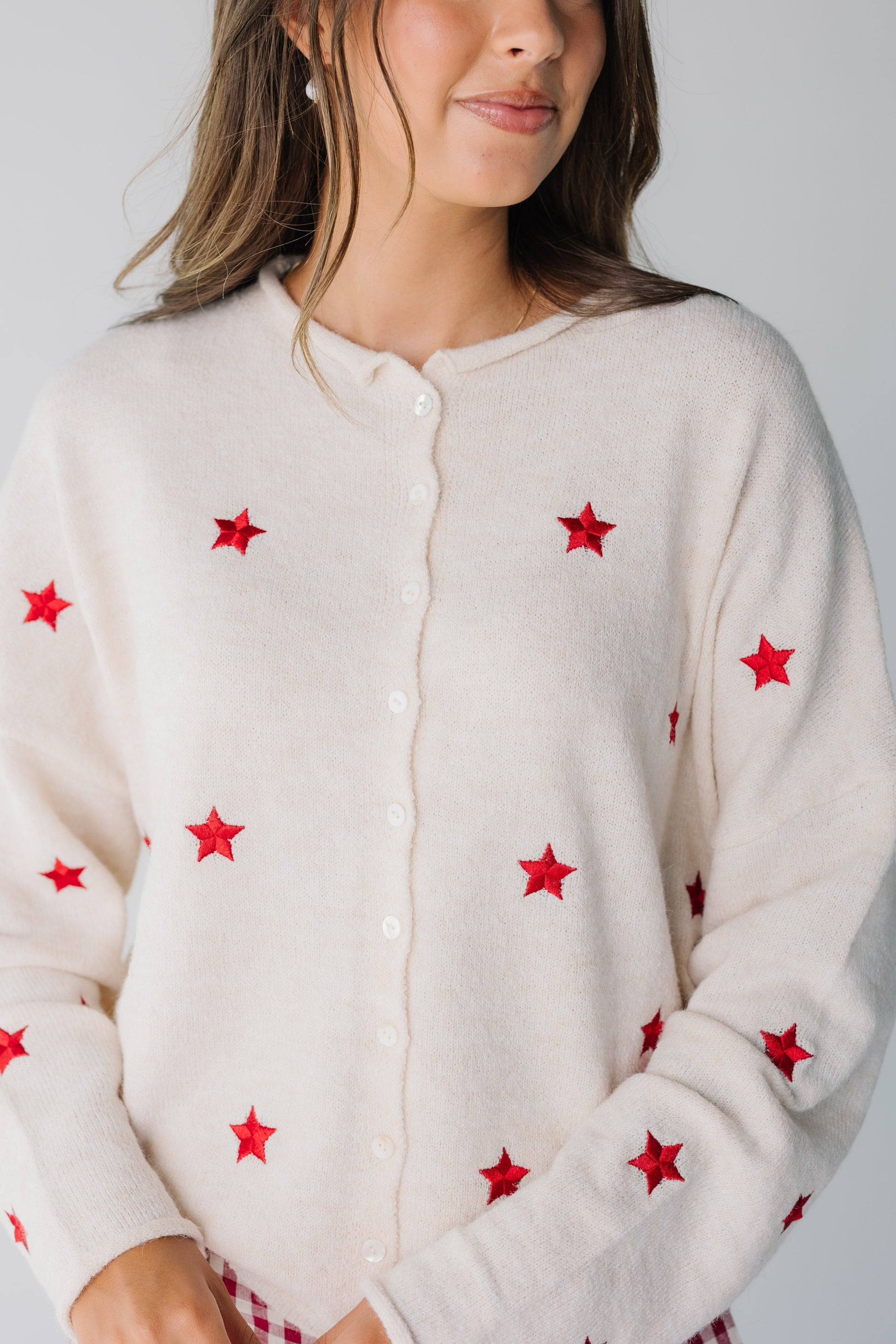 Close view of cream button down cardigan with red embroidered stars