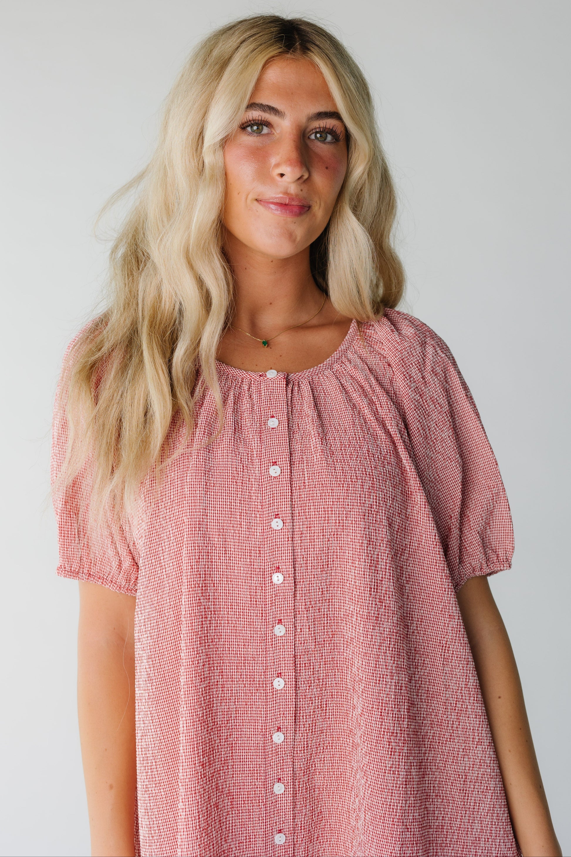 Close view of red gingham button down dress with round neckline