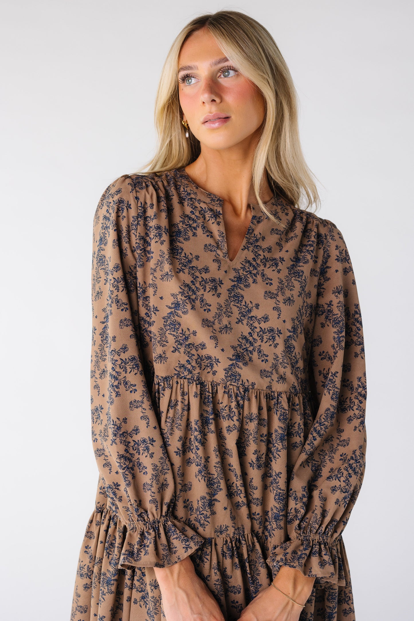 Close view of a woman wearing a brown loose dress with blue floral print