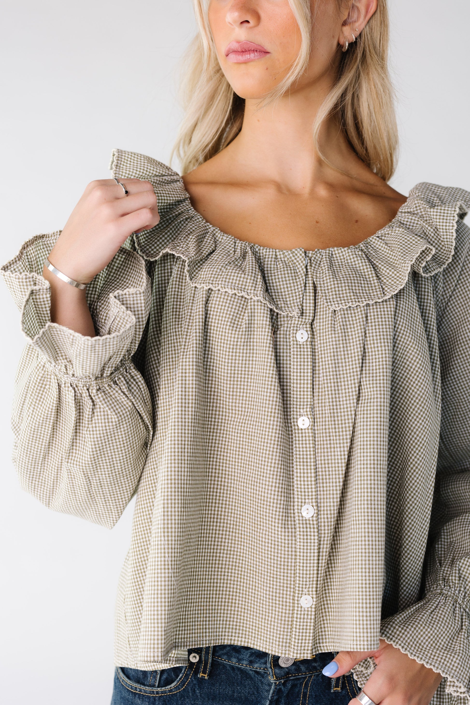 Close view of a woman wearing a sage gingham top with long sleeves