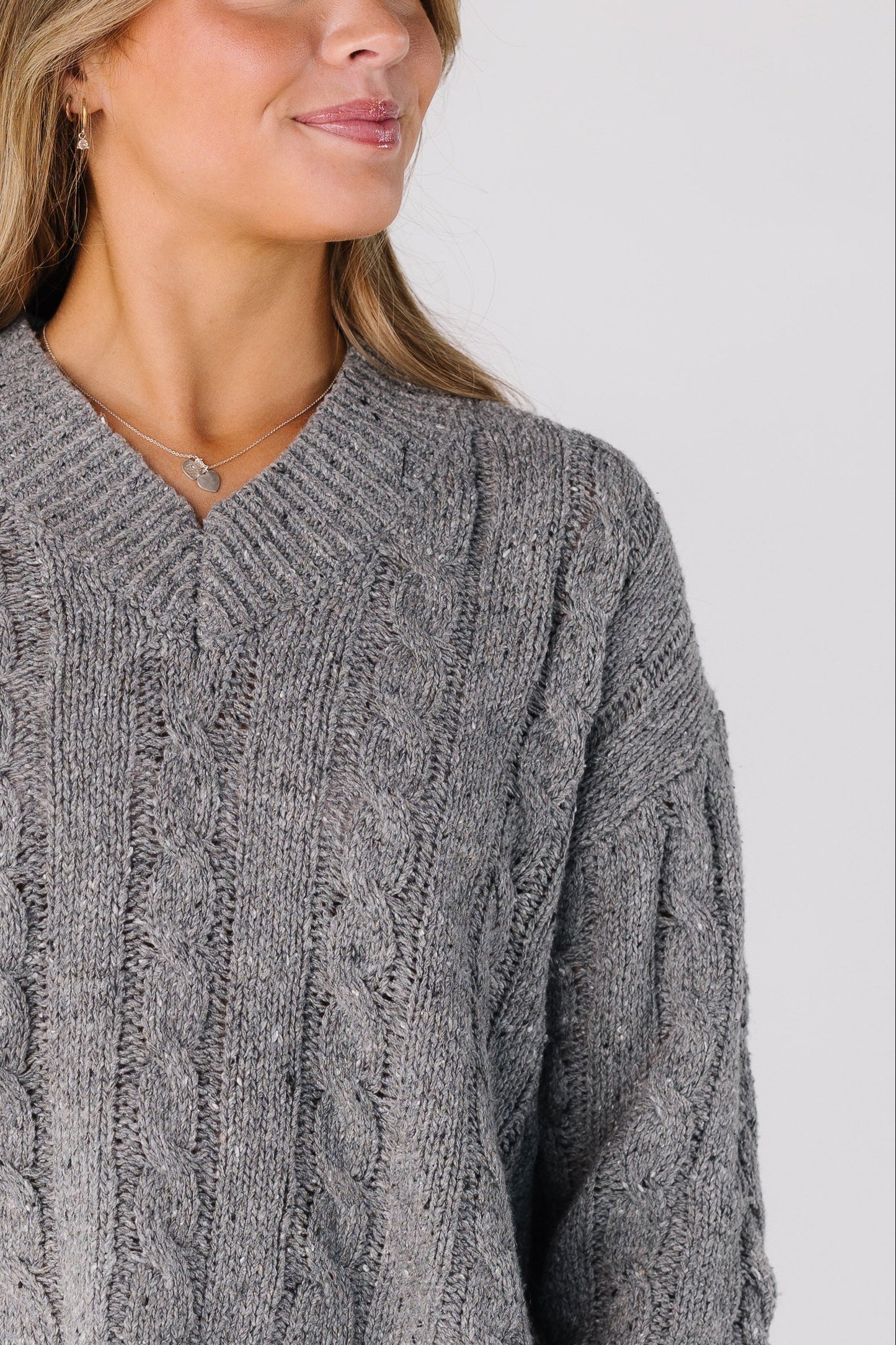 Close view of a women wearing a grey cable knit sweater