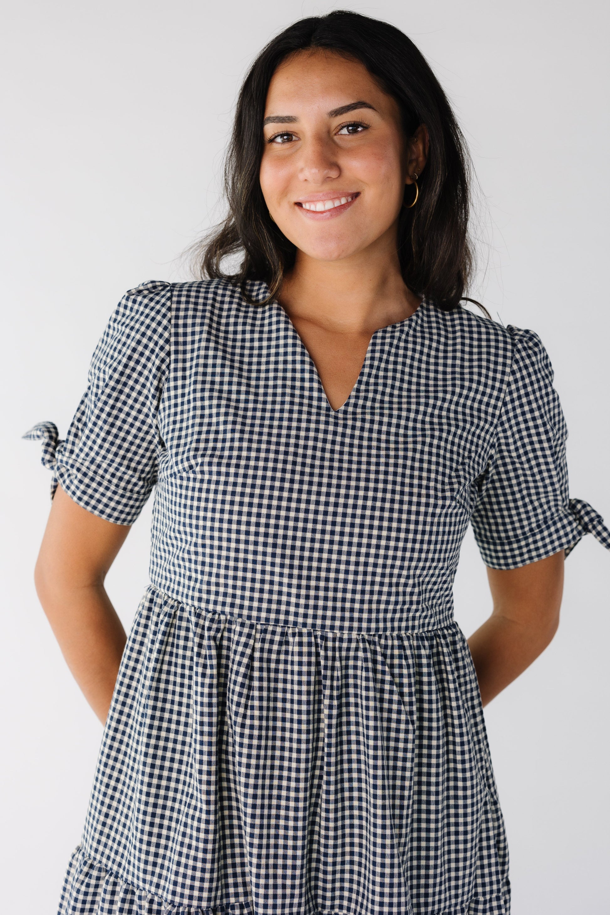 Close view of a woman wearing a navy gingham dress with notched neckline