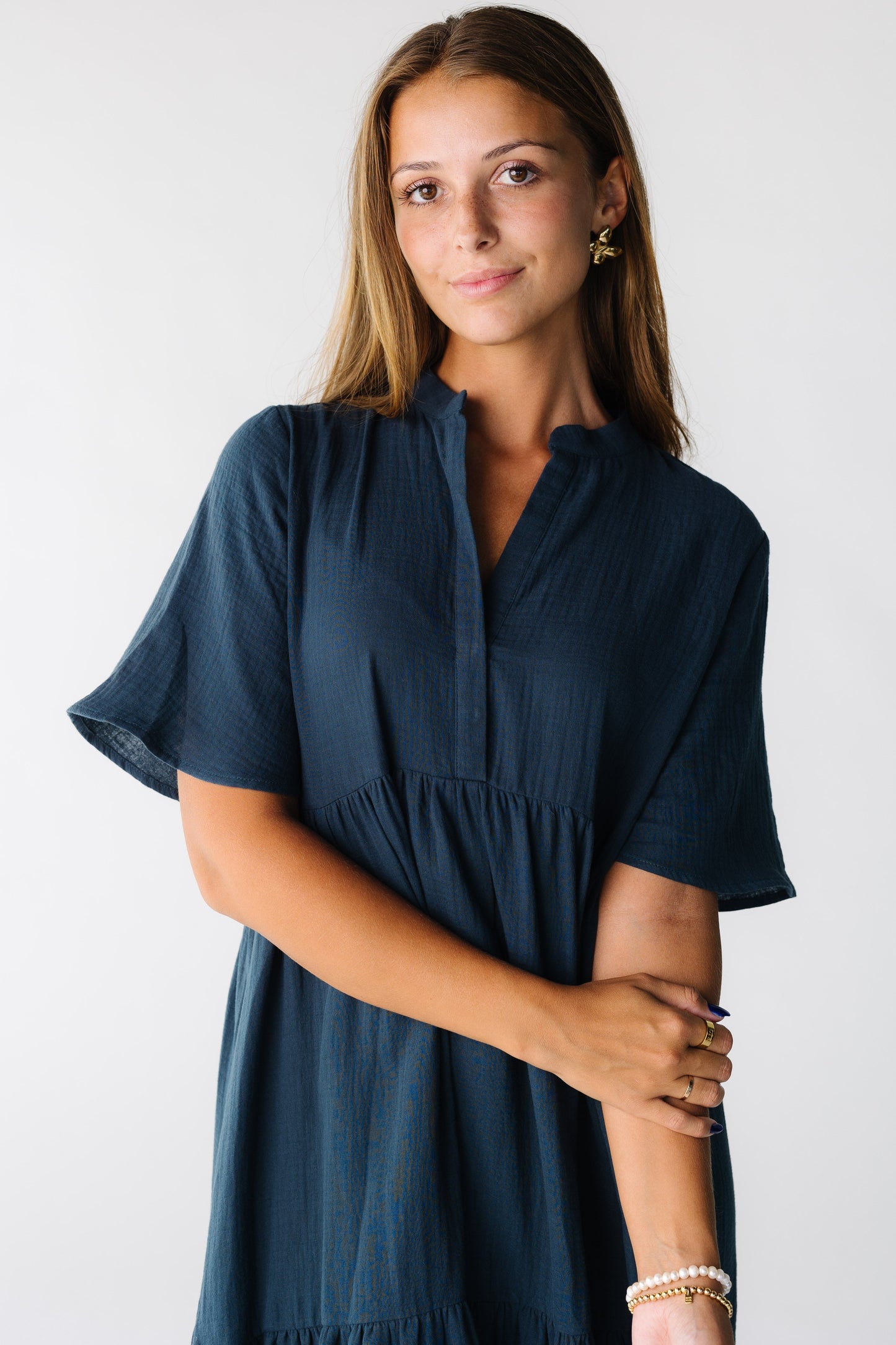 Close view of a woman wearing a dark teal dress with V-neckline and short sleeves