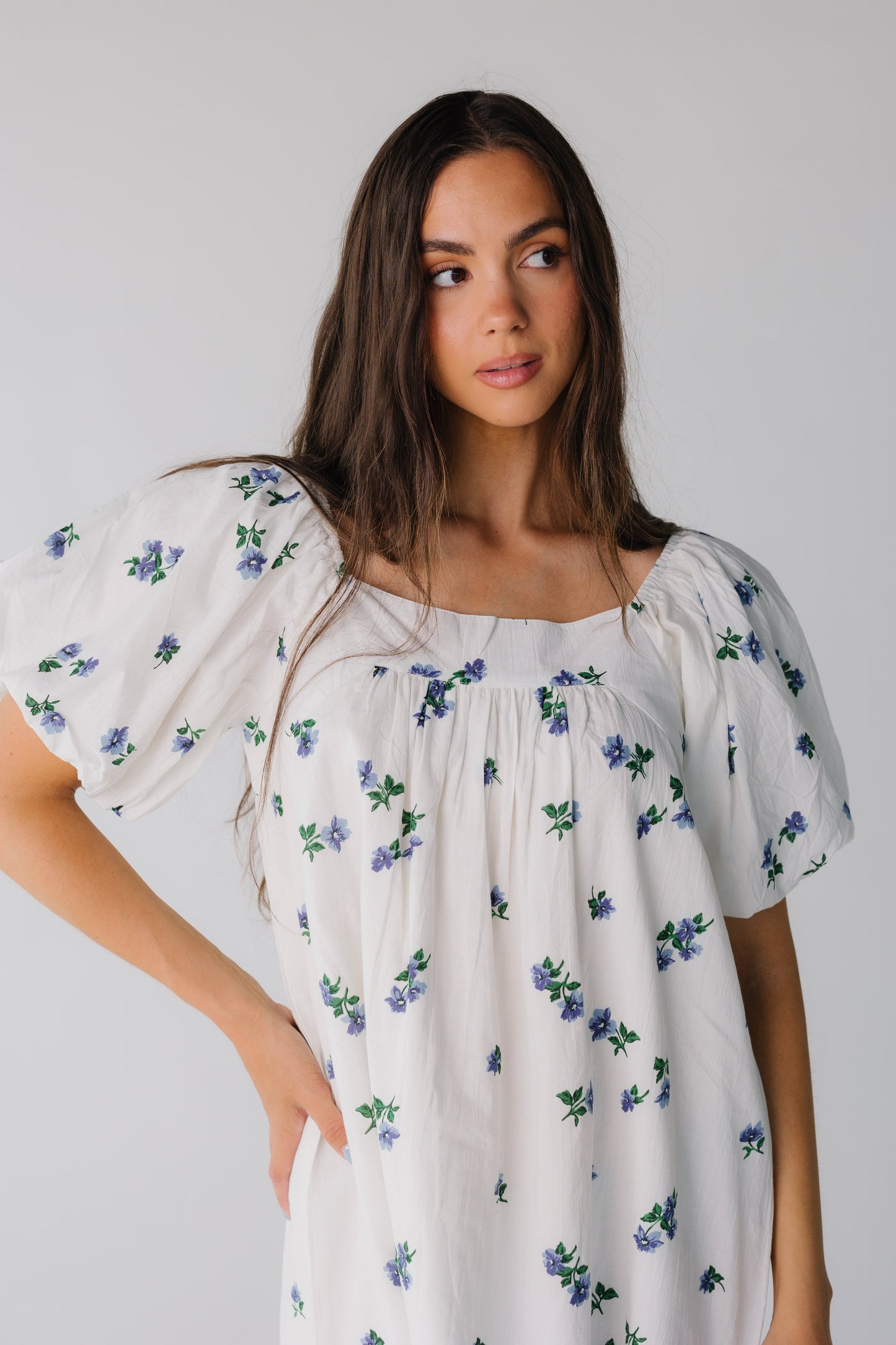 Close view of white dress with blue floral print and square neckline