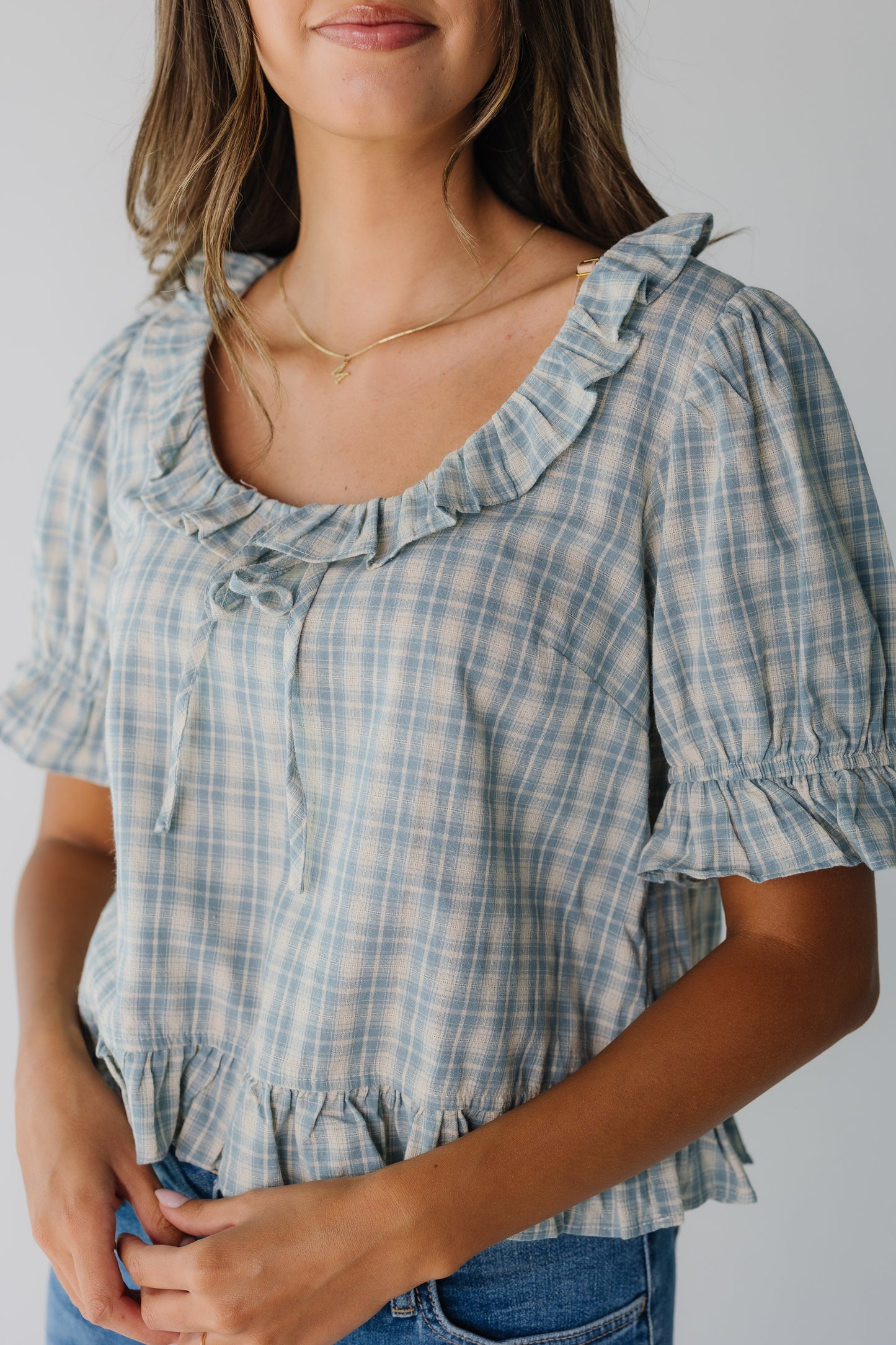Close up of blue plaid top with ruffles and short sleeves