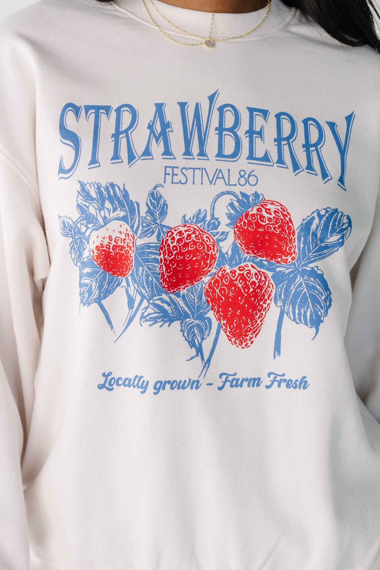 Close view of strawberry graphic on white sweatshirt