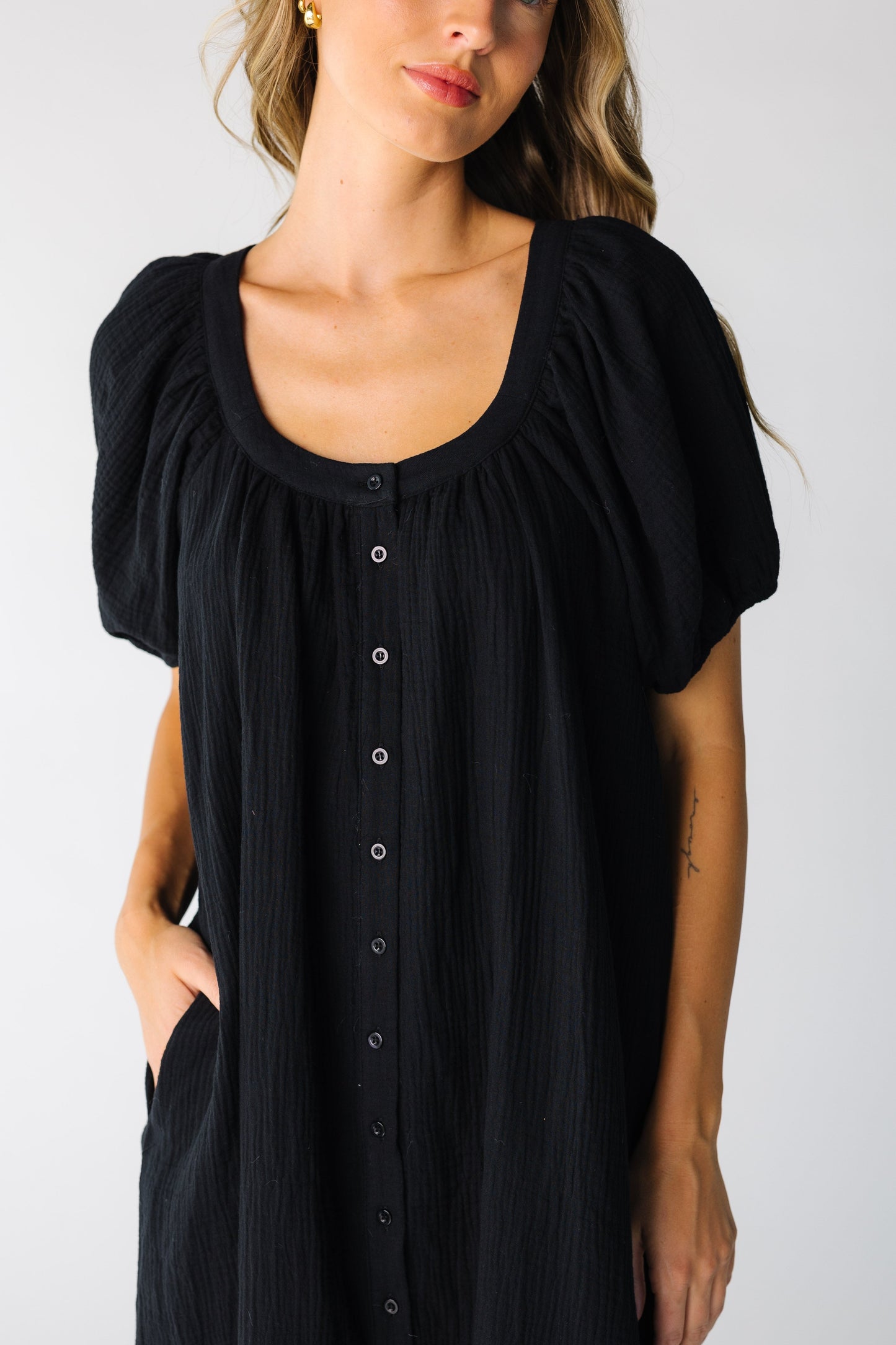 Close view of black button down dress with scoop neckline and side pockets
