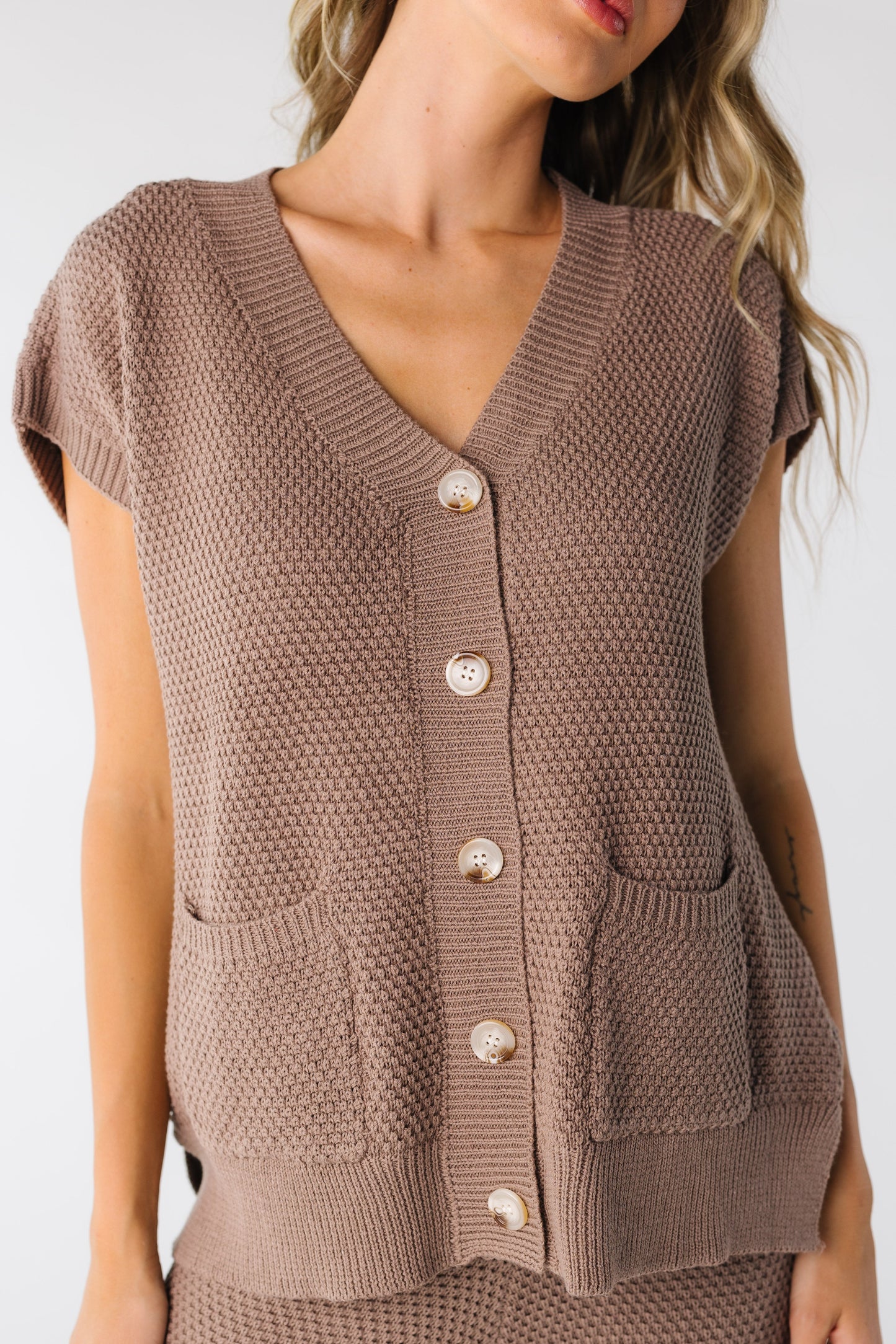 Close view of mocha waffle texture top with functioning buttons and 2 patch pockets