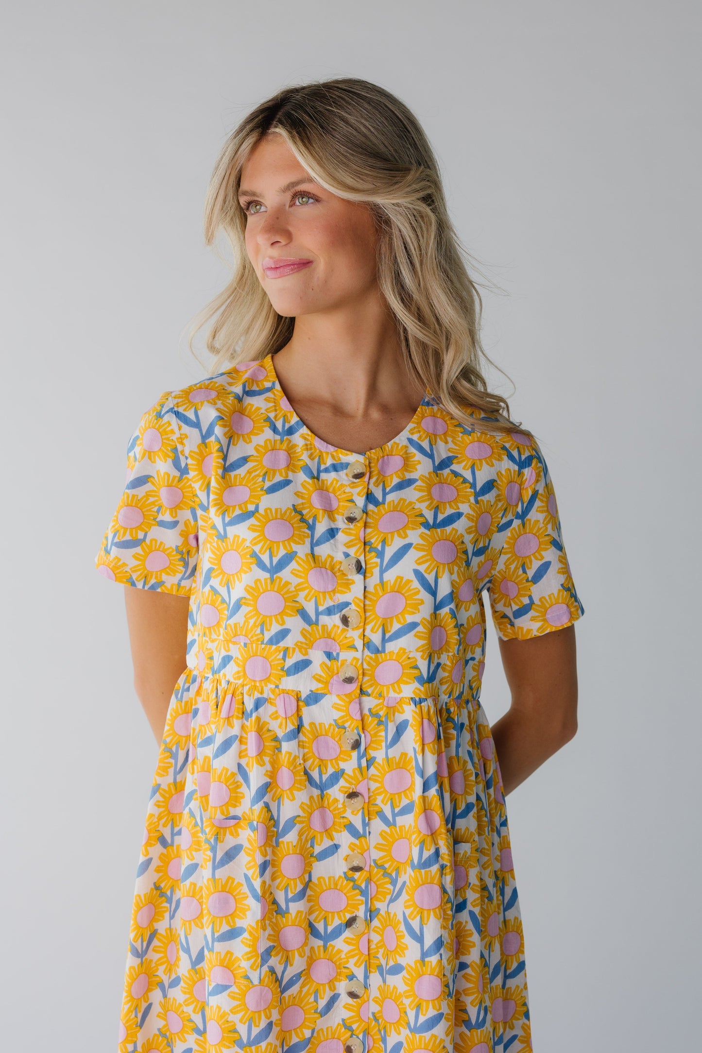 Close bodice view of button down yellow floral print dress with round neckline