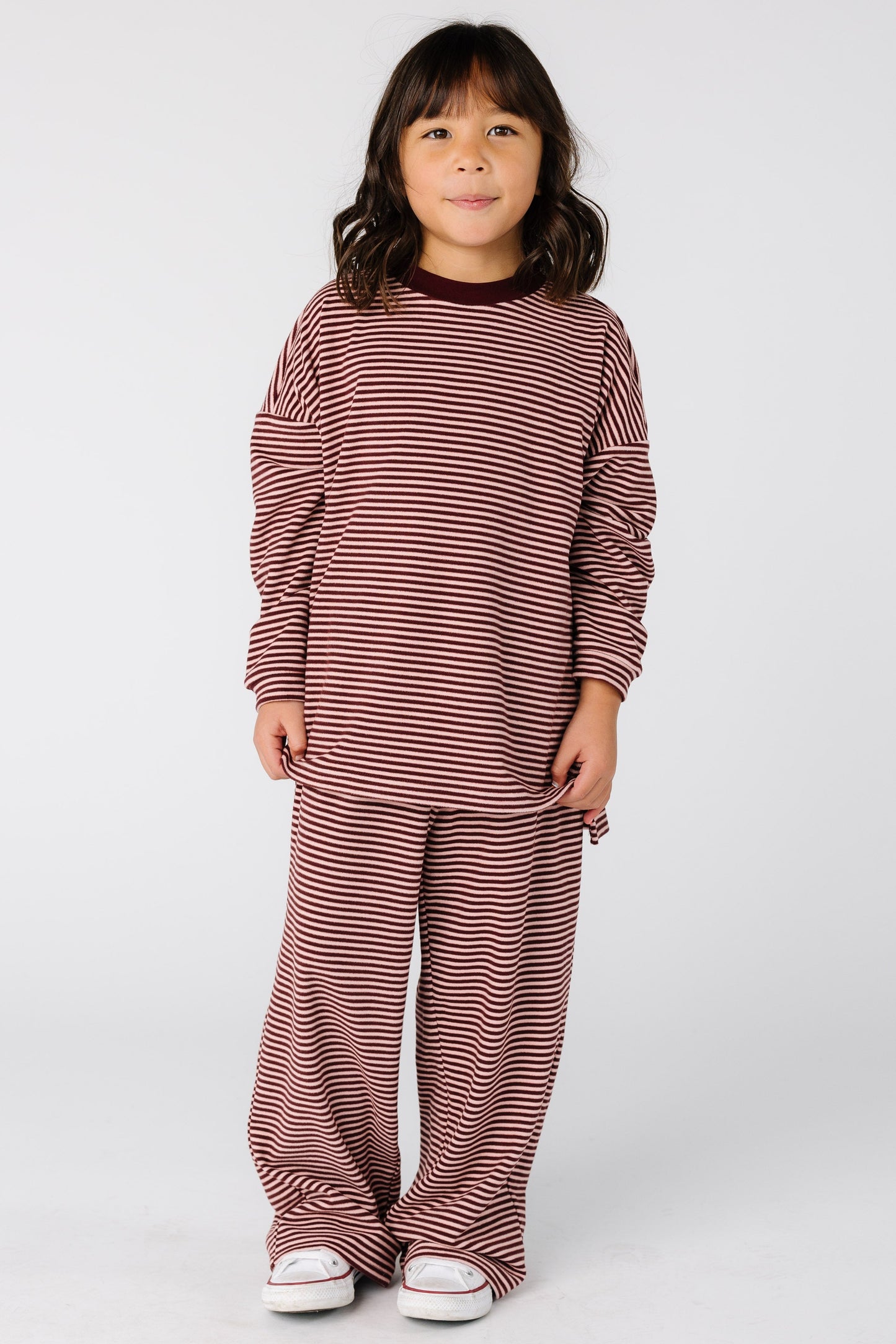 Girl wearing a modest stripe lounge set in burgundy with with long sleeves and full length pants