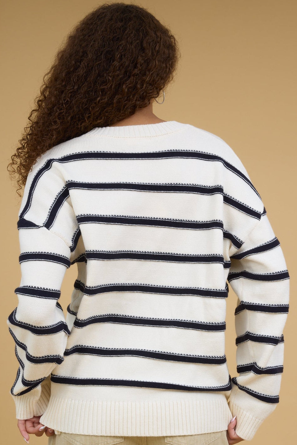 Back view of a woman wearing an ivory and navy stripe sweater.