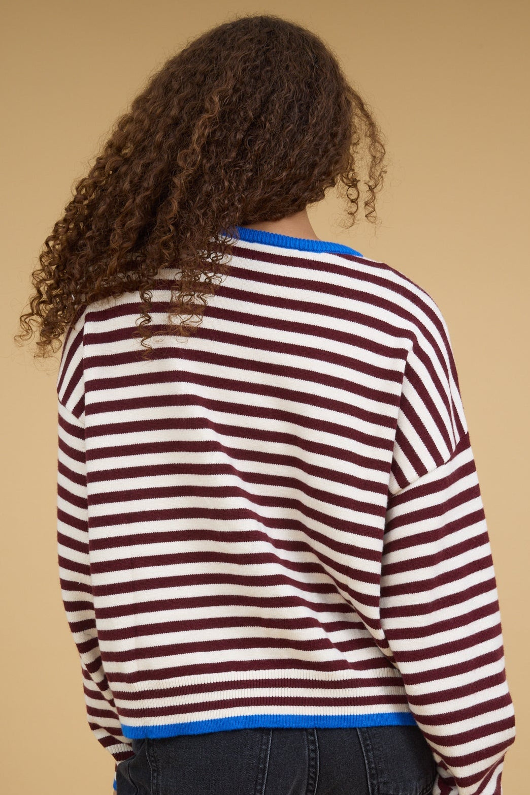 Back view of a teenage girl wearing a loose fitting stripe top in burgundy & cream.