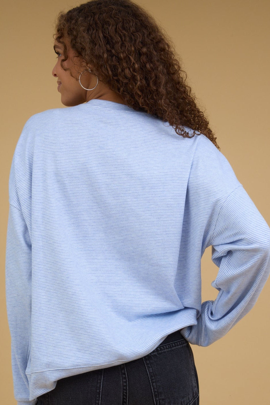 Back view of a woman wearing a light blue & white stripe sweatshirt.