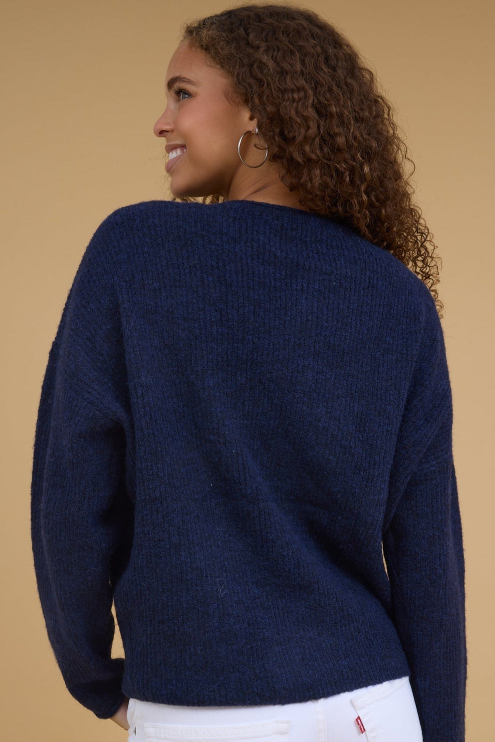 Back view of a woman wearing a navy rib knit cardigan with long sleeves.