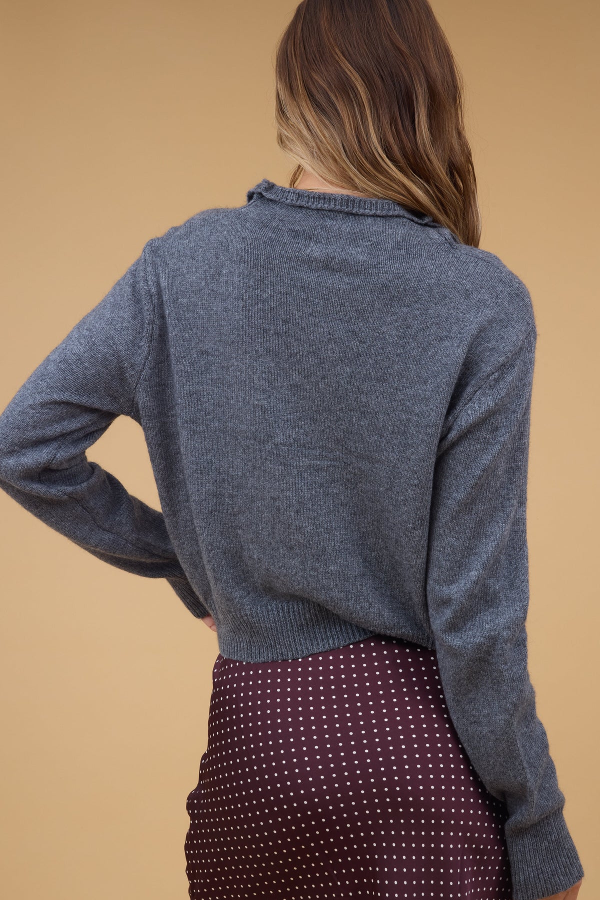 Back view of a woman wearing a grey long sleeve cardigan.